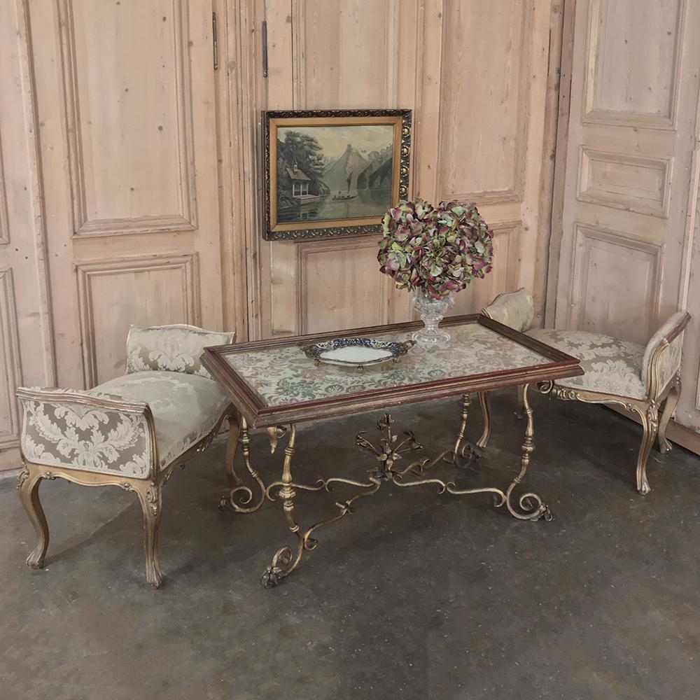 Antique Italian wrought iron and glass top coffee table is a marvel of the metalsmith's art, with intricately scrolled and embellished wrought iron serving as a stylish base, and a wood-framed glass top which allows one to see the fabric underneath,