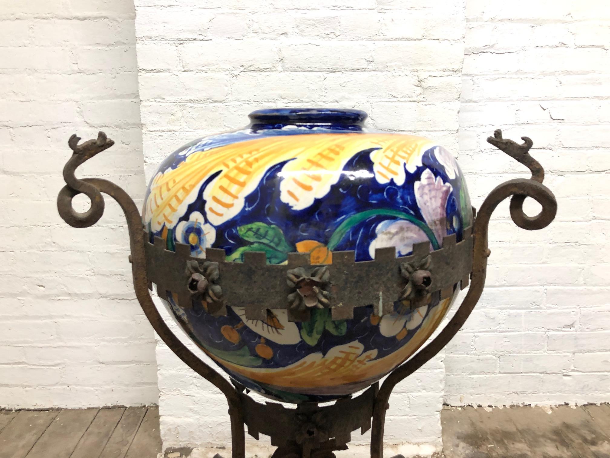 Antique, Italian wrought iron planter with hand painted Majolica vase. Wrought iron base has dragon heads to the top, a floral pattern and the vase is hand painted Majolica.