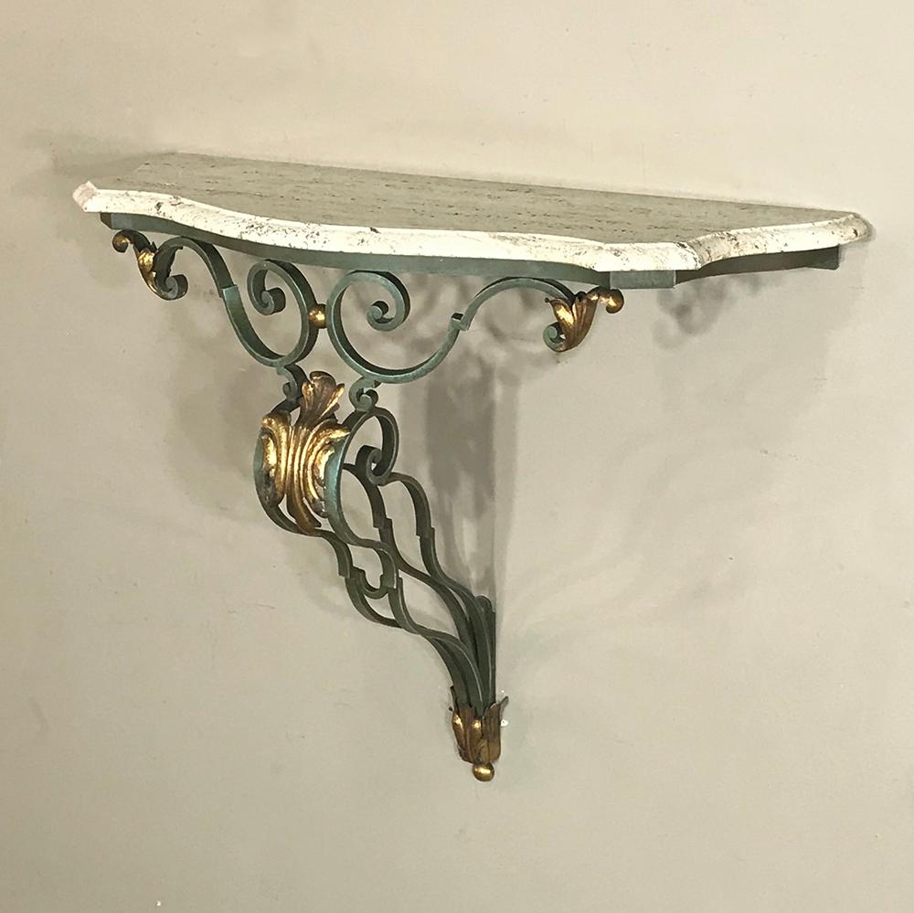 Antique Italian wrought iron and travertine console was designed to mount on the wall, and makes an elegant surface upon which one can decorate or place candles. Gold painted highlights on the acanthus plume ornamentation enhance the rich patinated