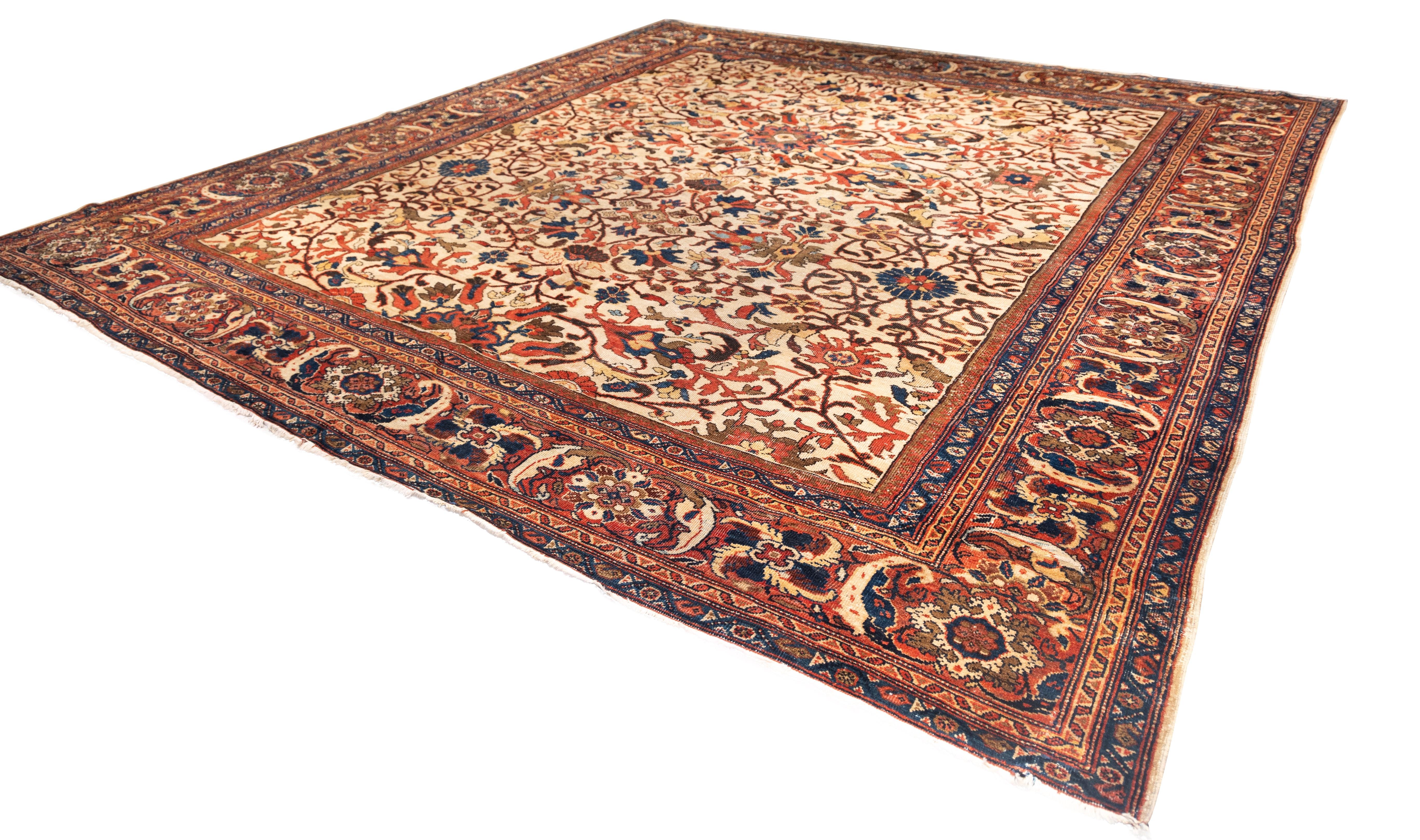 early 20th-century Mahal carpet presents a striking allover arabesque pattern centered on a cream ground. The field is filled with scrolling vinery, serrated leaves, and palmettes in rust red, navy, ochre, and forest green. The symmetrical design is