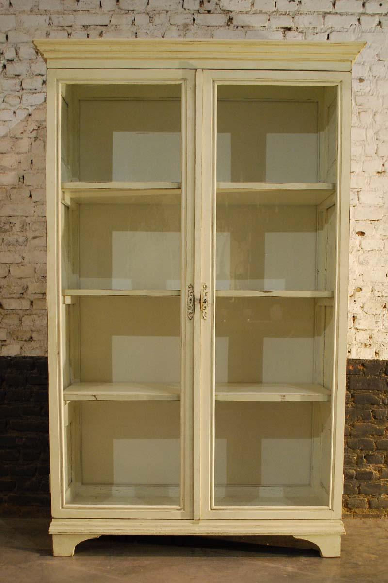 A beautiful rustic German two-door painted two-door cabinet. 
This cabinet is made in oak and has three panels per side. The doors have glass panels, showing the interior of the cabinet. 
It has three fixed shelves. The interior is recently