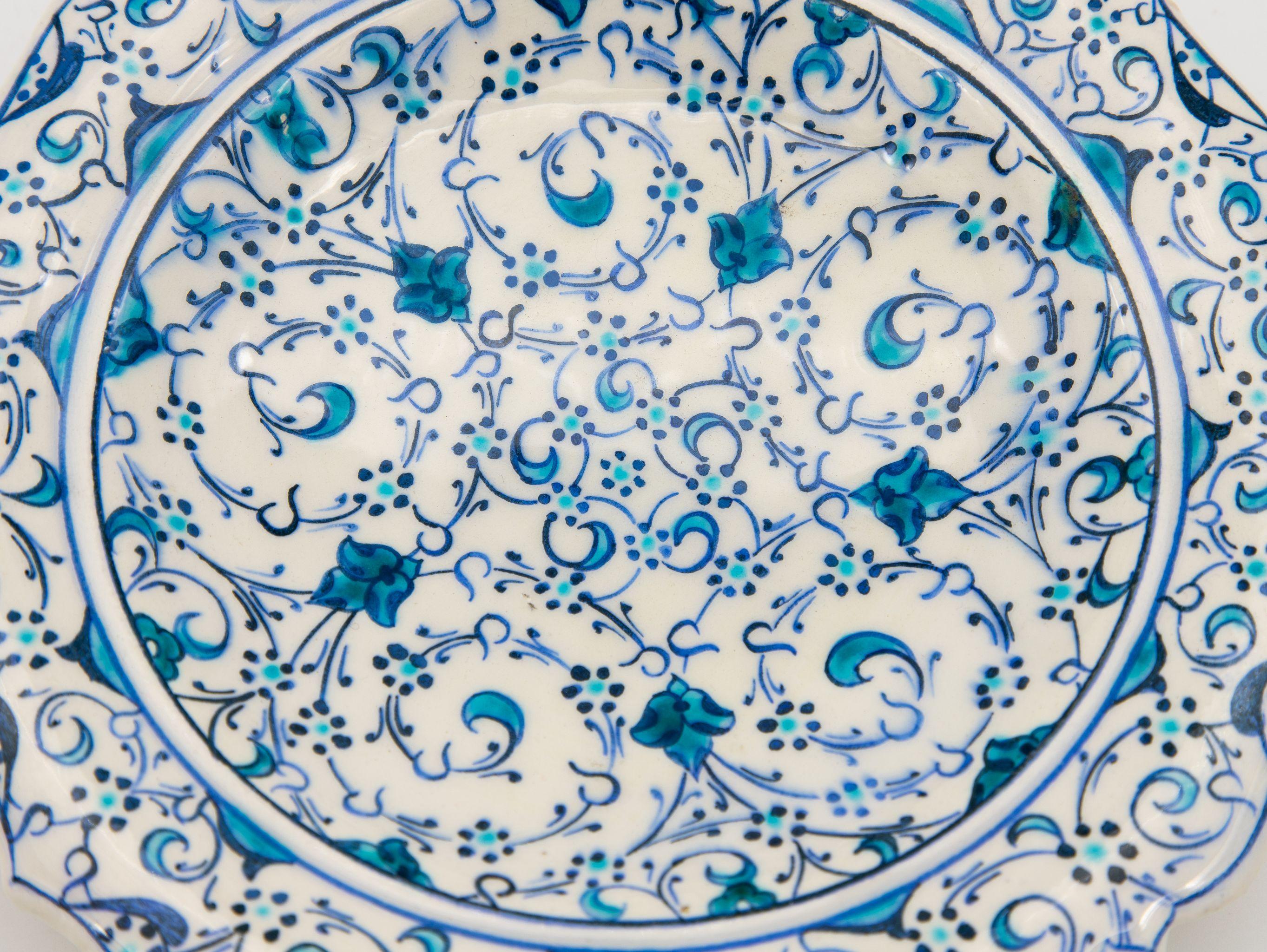 A stunning small Iznik plate in a piecrust shape. This beautiful example of early 20th century Iznik pottery features the iconic cobalt and turquoise colors on white background that this Turkish style of pottery is known for. There is repeating