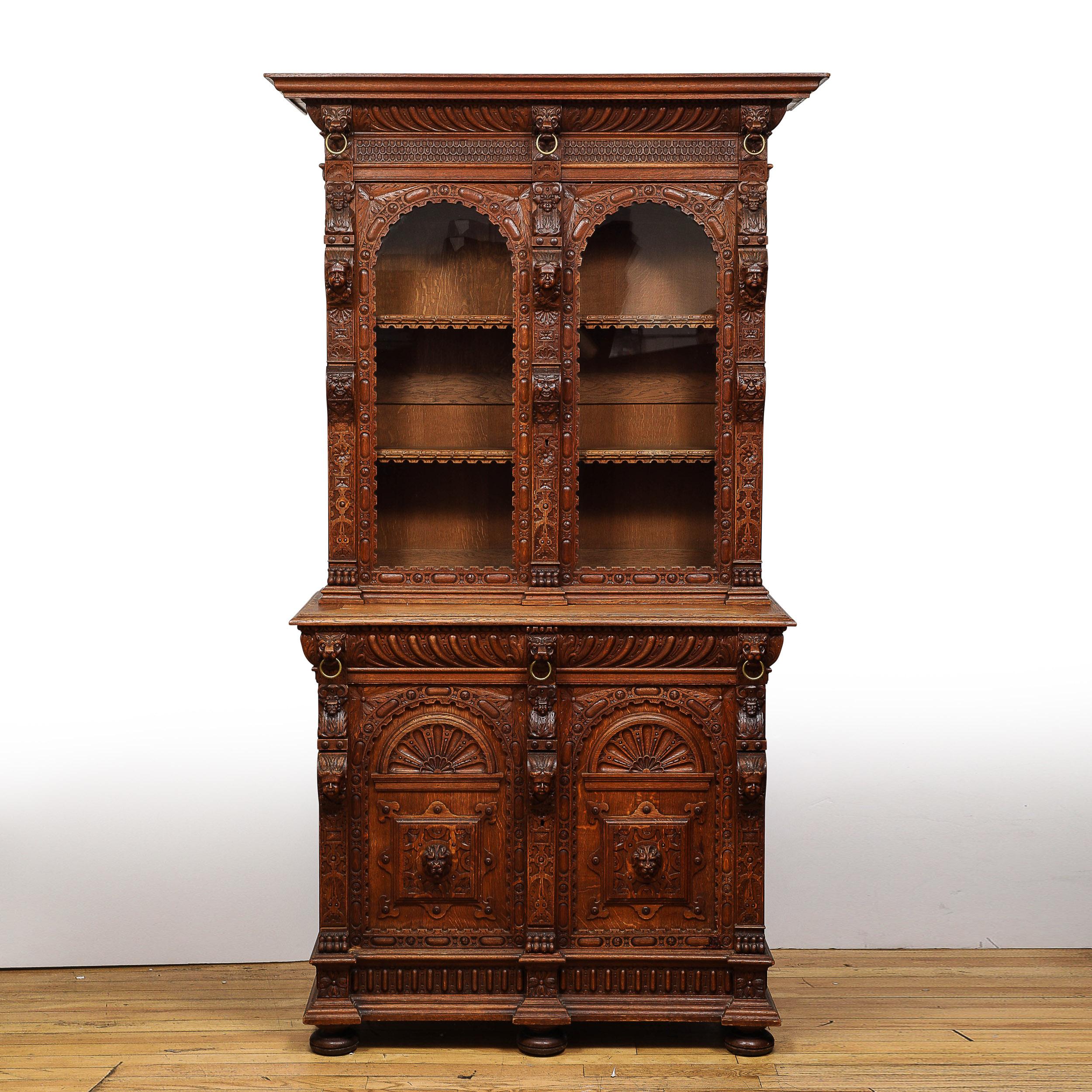 This elegant and brilliantly carved Jacobean Carved Oak Cabinet originates from the United States, Circa 1890. This piece features a beautiful two-tiered structure with a stepped plinth base and three bun footed supports, the lower section