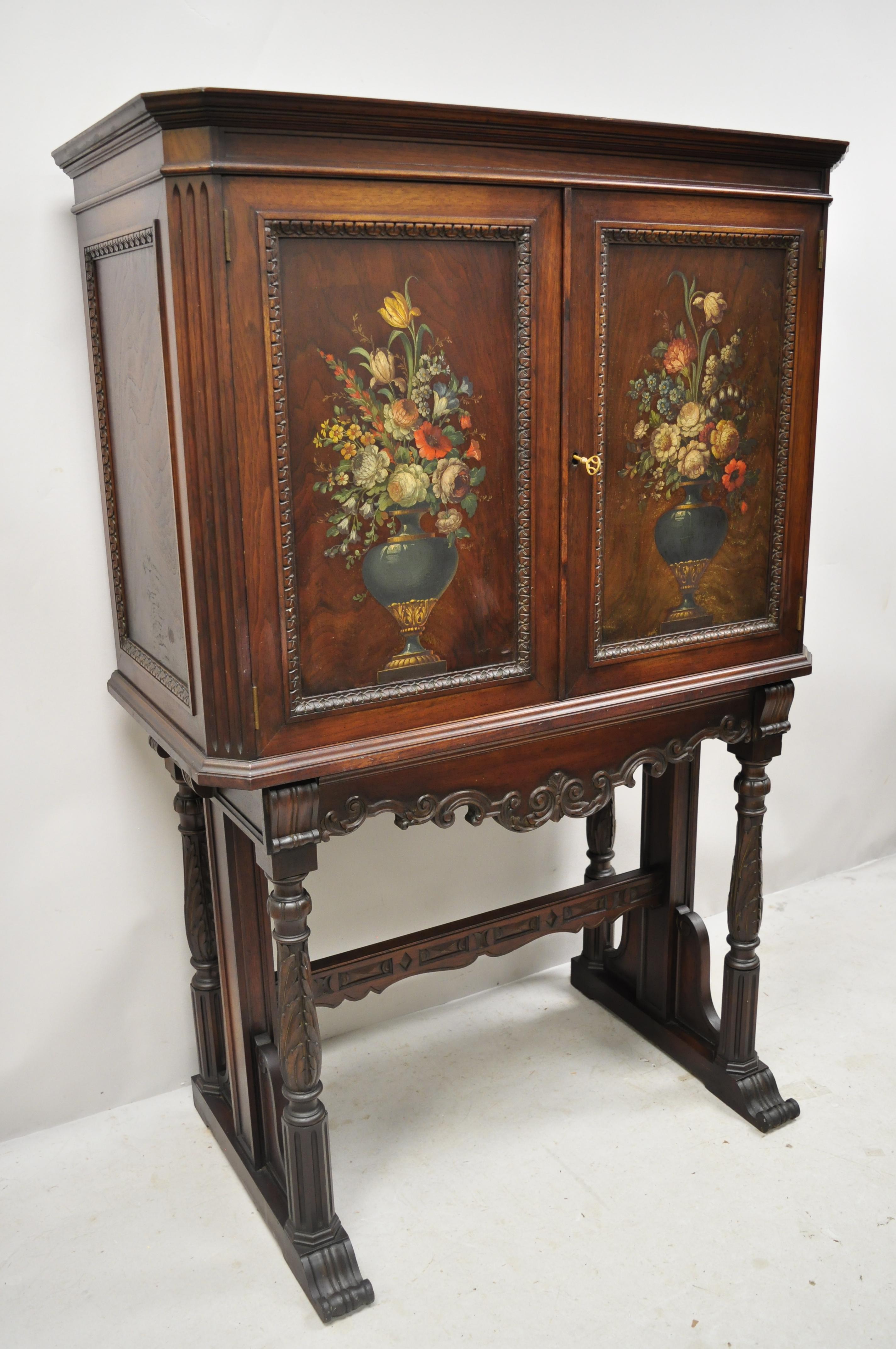 Antique Jacobean floral hand painted carved walnut blind door cupboard cabinet. Item features hand painted flower arrangements to door fronts, pull out tray surface, beautiful wood grain, nicely carved details, 2 swing doors, working lock and key,