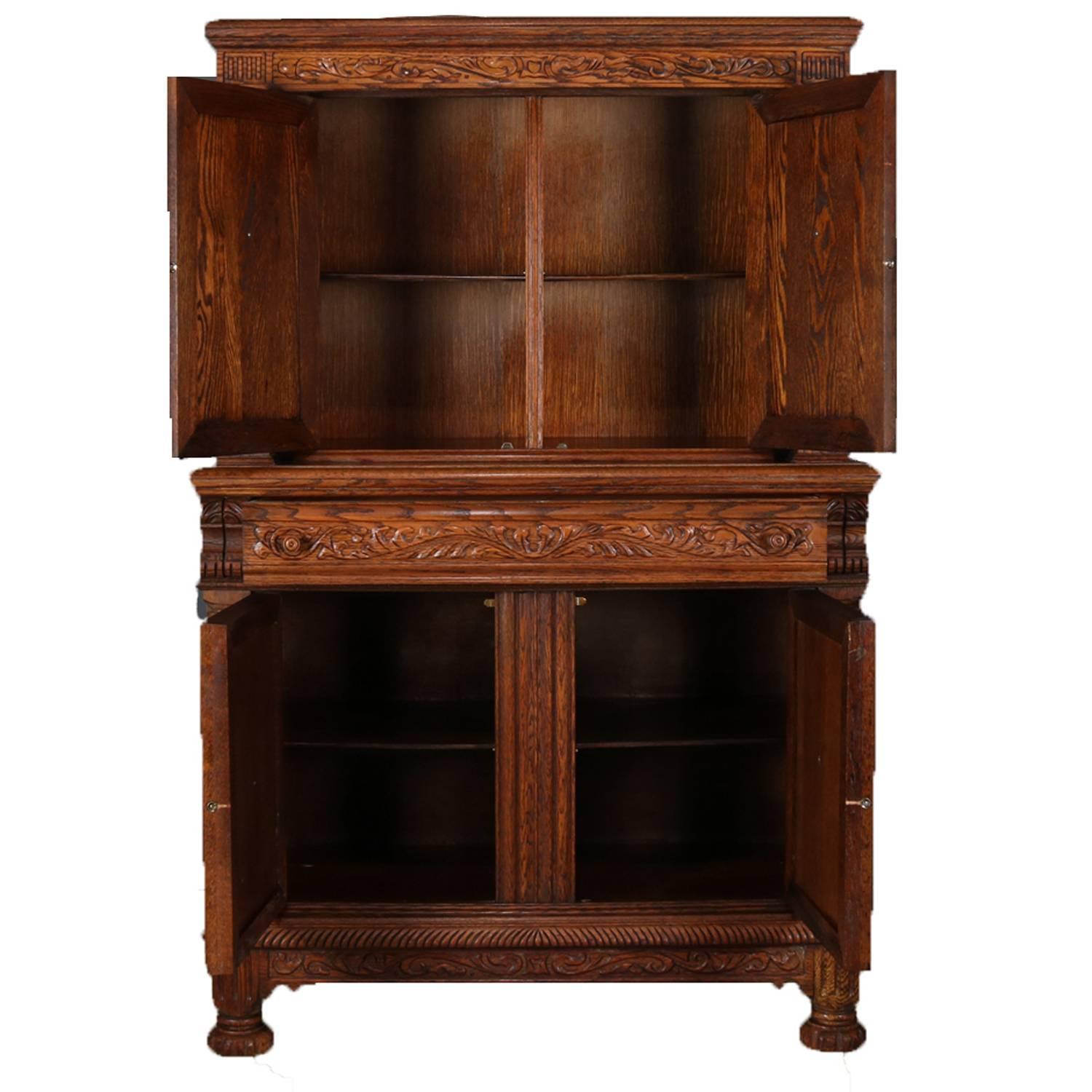 Carved oak Jacobean step back cupboard features upper cabinet having doors with heavily carved scroll and foliate motif and bookmatched insets flanked by barley twist columns, lower cabinet having arched panels with bookmatched burl and framed with