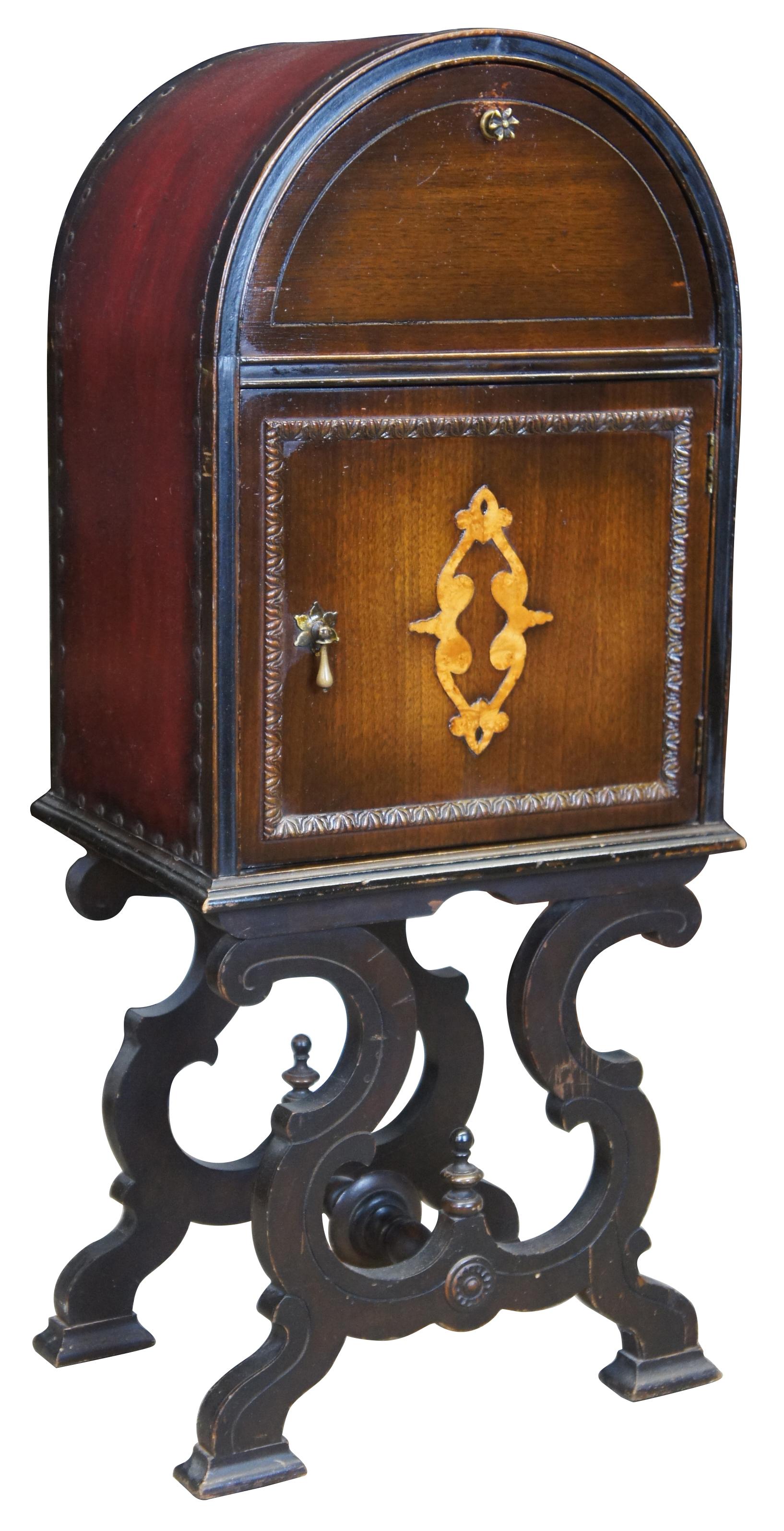 Early 20th century Spanish or Jacobean revival smoking cabinet. Features a domed cabinet with tin lined humidor and upper compartment for storage, over an ornate trestle style spooled base. Made from walnut with a leather exterior featuring nailhead