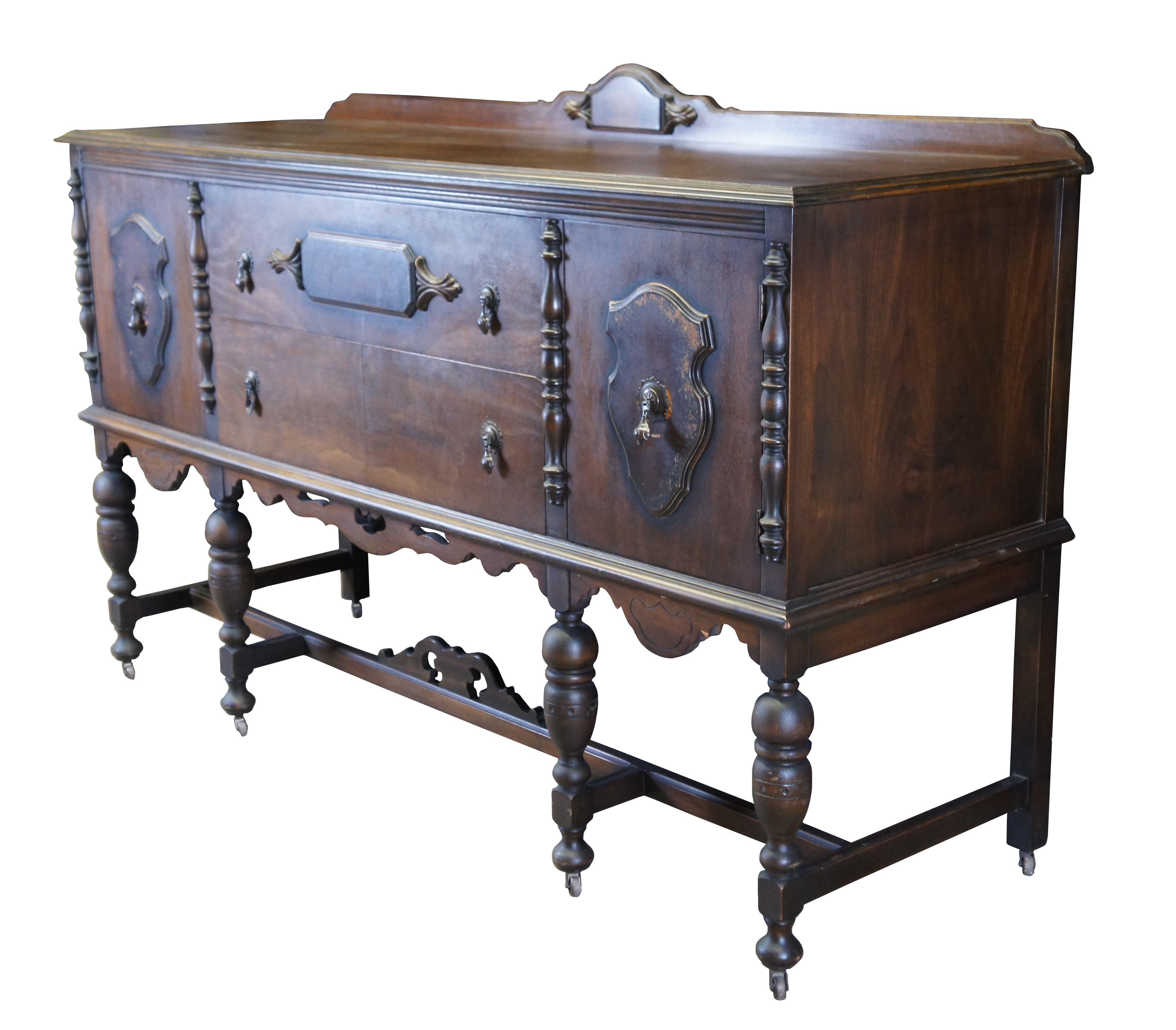 Antique Jacobean / Spanish Revival style buffet or sideboard.  Made of mahogany featuring rectangular form with serpentine backsplash and paneled accents over large drawers flanked by cabinets.  The buffet is supported by turned legs connected by