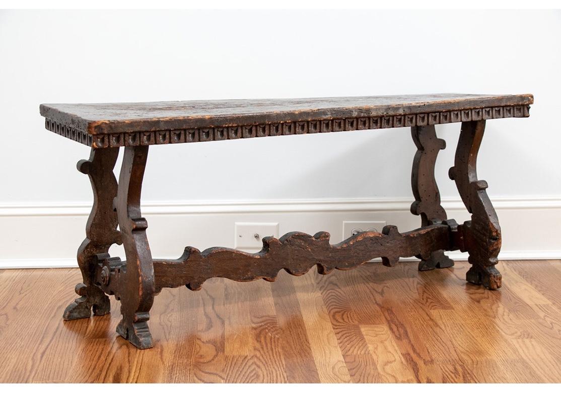 Possibly English. A well-worn bench with carved top edge and raised on elaborately carved and shaped legs with a flat carved and scrolled long stretcher.
Measures: Length 43 1/2