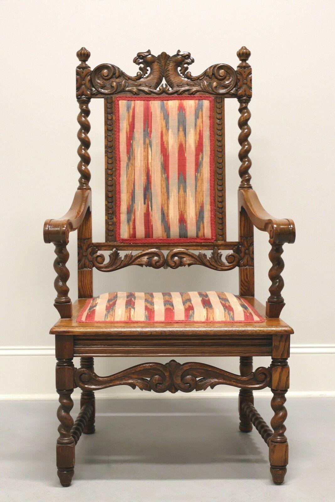 An antique Jacobean style open armchair, unbranded. Tiger oak with flame stripe fabric upholstered back and seat. Intricately carved details on back and apron with carved griffins at top. Barley twist on chair back, arm supports, stretchers and