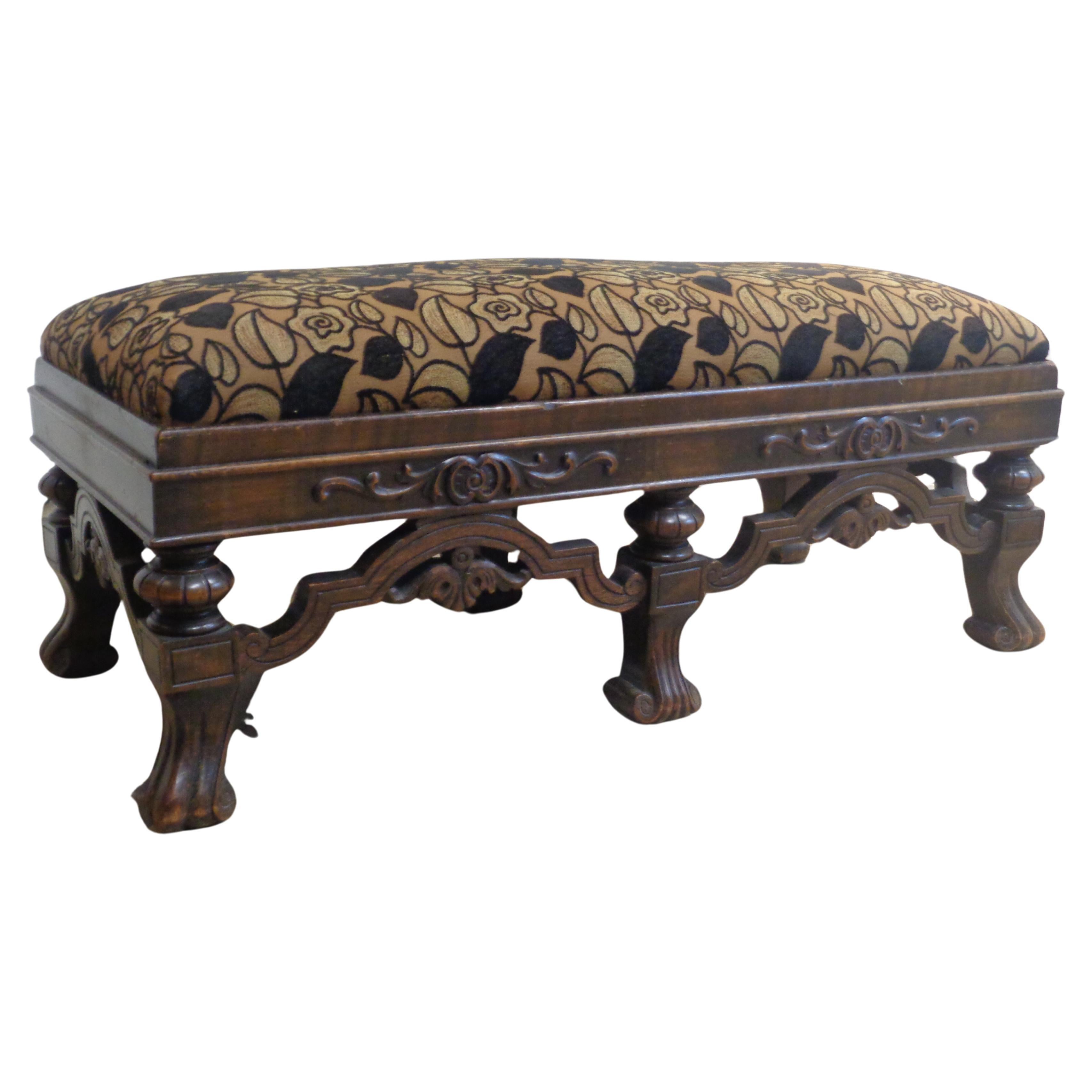 Jacobean style carved walnut fireside bench in nicely aged original color patina w/ exceptionally beautiful crewelwork embroidered upholstered seat. Very good quality. Circa 1920-1940.  Measures 42