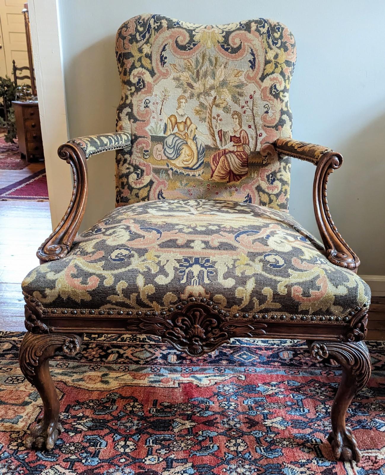 A beautifully carved antique throne or hall chair in the Jacobean style with medieval scenery needlepoint. European circa early 1900's, either French or Italian with a stunning classic design. Features carved wood and brass nail head trim around the