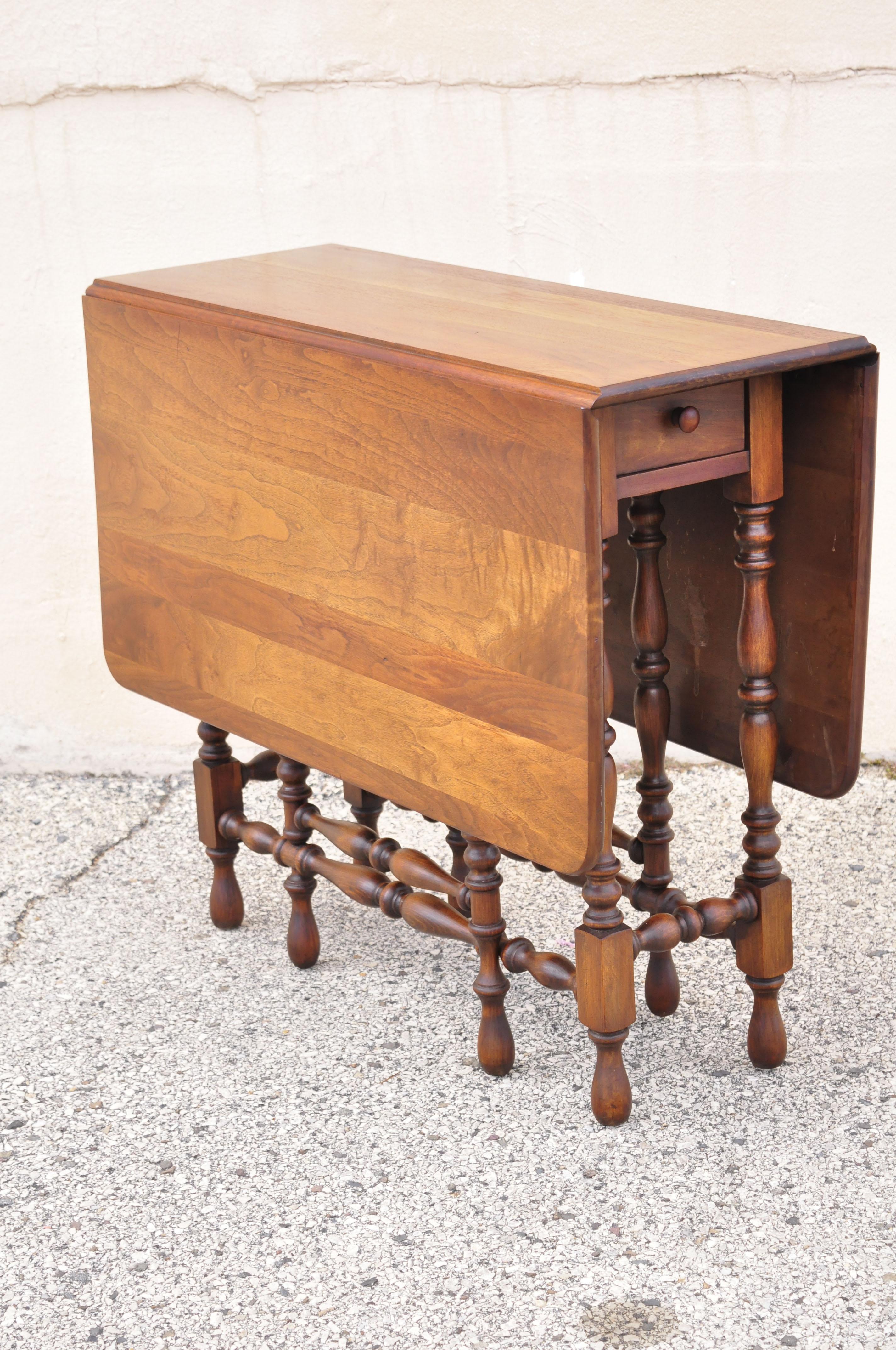 Antique Jacobean walnut drop leaf gate leg dining table with drawer by Brandt. Item features drop leaf sides with gate leg base, solid wood construction, beautiful wood grain, original label, 1 drawer, very nice antique item, quality American