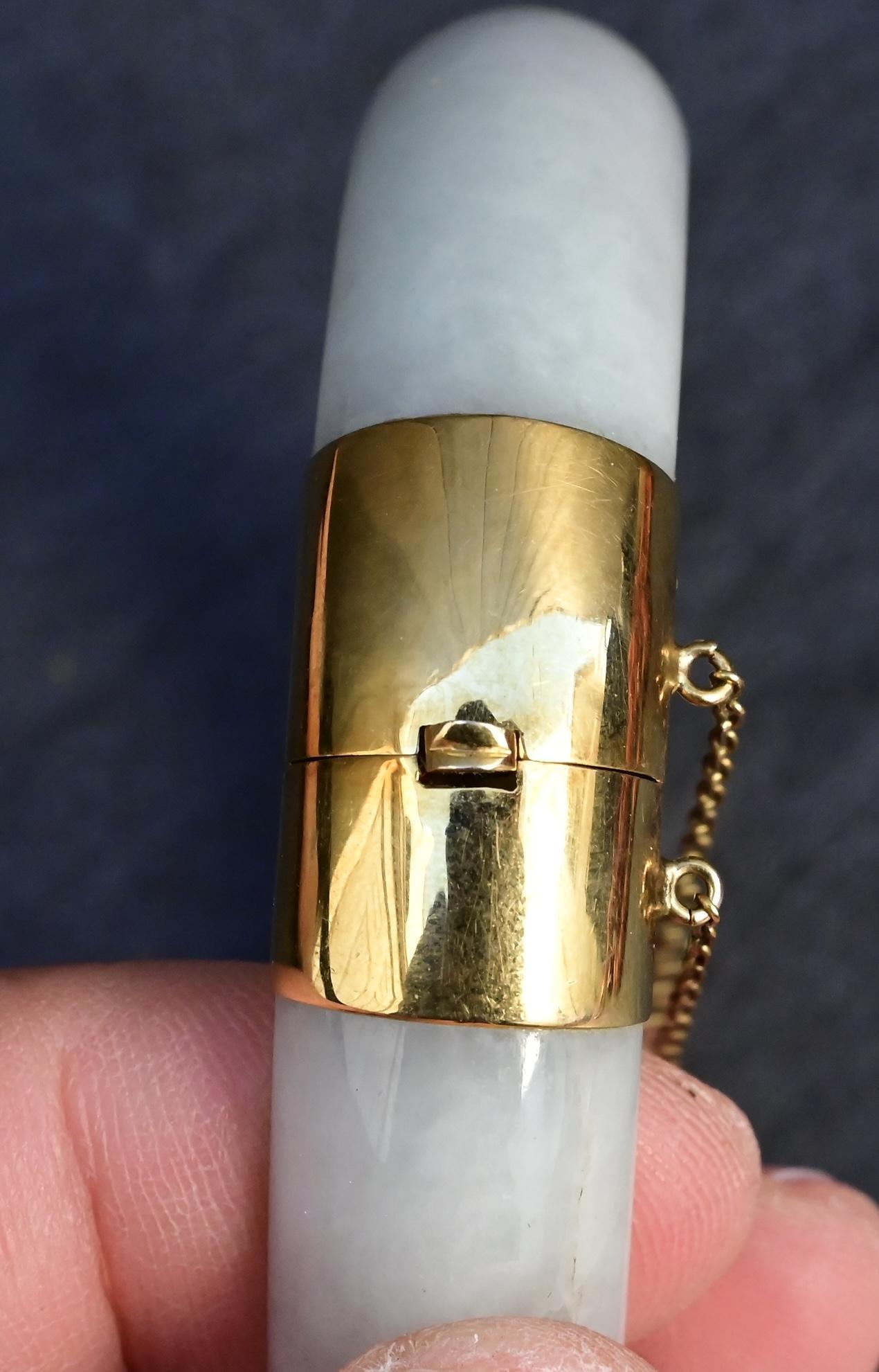 Cet exquis bracelet antique met en valeur l'élégance intemporelle du jade naturel, magnifiquement complété par des accents d'or 14K. Le bracelet présente une bande de jade lisse et arrondie d'une douce teinte vert pâle, qui symbolise la pureté et la
