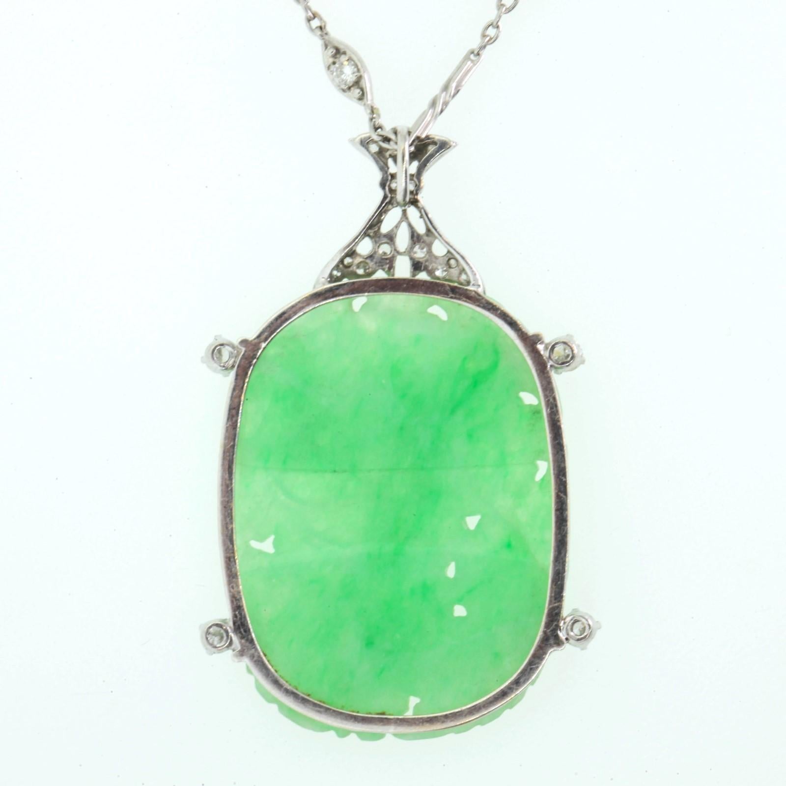 A beautiful 1930s carved, cushion shape natural Jade plaque set in a platinum frame with a diamond filigree finial.  The Jade is surrounded by four Transitional cut Diamonds, all weighing 0.40 carat.   The pendant is suspended from a and made