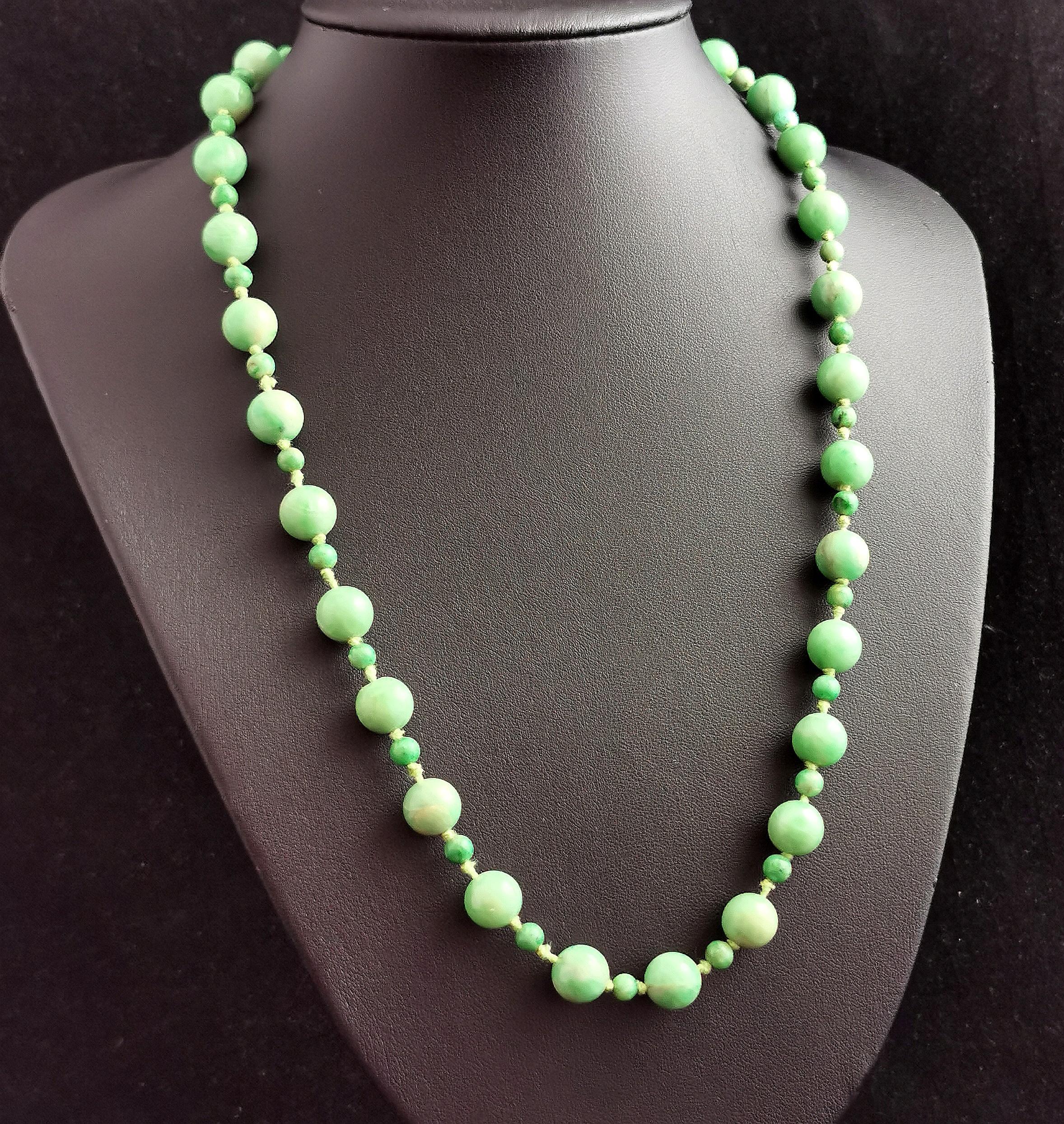 A beautiful antique Art Deco era Jadeite Jade bead necklace.

Lovely apple green beads, with beautiful variations in the colourway from almost white to darker green streaks, all delicately hand shaped and tightly knotted onto a cotton thread.

The