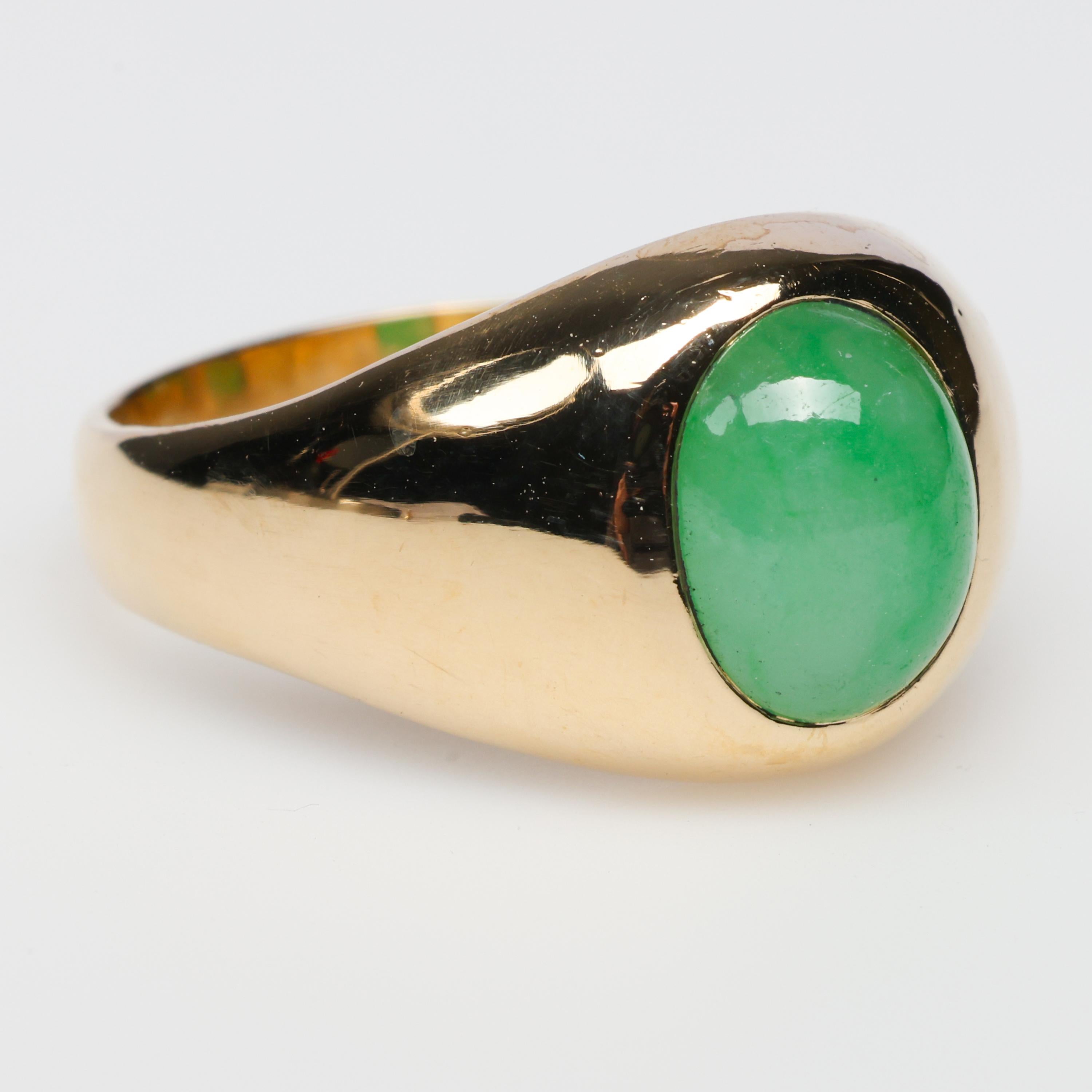 This antique 14K yellow gold ring features a bright green cabochon of natural and untreated apple green jadeite jade.  Tye stone measures 8.8 x 7.5 x 3.92mm and is translucent and slightly mottled. The classic styling of this ring is the 1920s