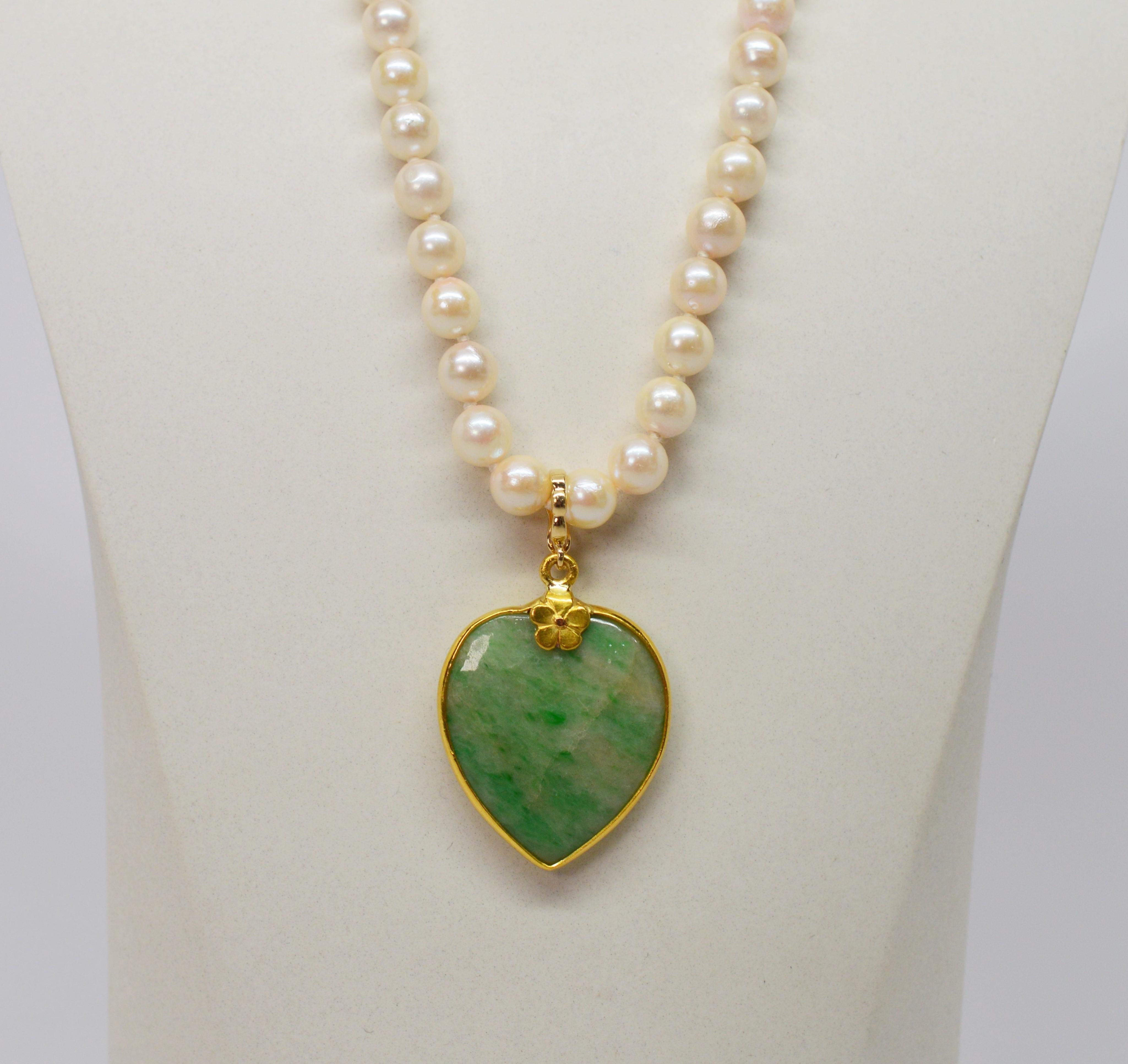 This romantic antique piece features a soft green natural jade heart pendant framed in fourteen karat gold suspended on an eighteen inch classic
strand of 5-1/2mm x 6mm pearls finished with a decorative fourteen karat gold barrel clasp. The jade