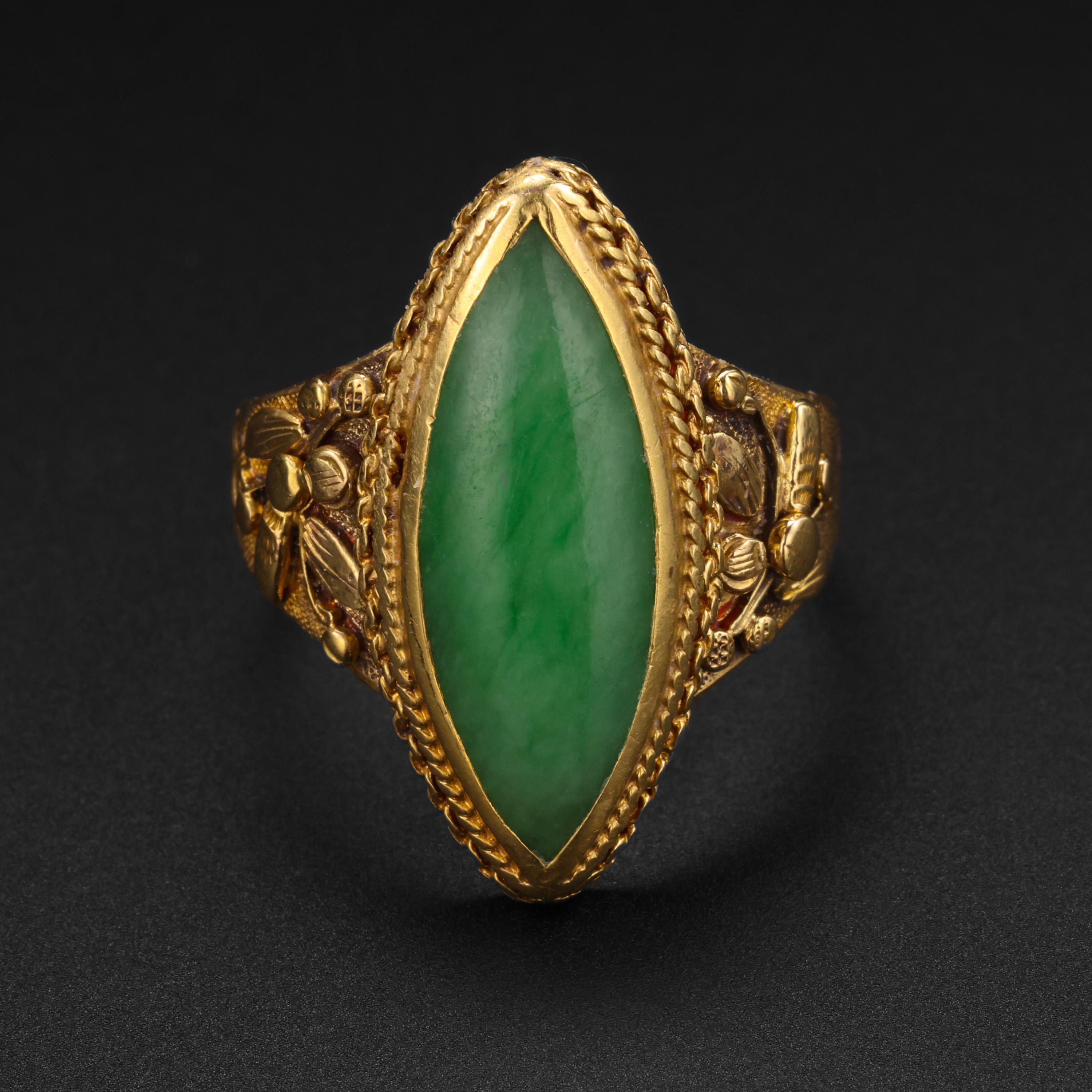 Dieser Ring aus reichem, butterweichem 18-karätigem Gelbgold und Jade wurde gegen Ende des 19. Jahrhunderts in China von Hand gefertigt. Auf den kunstvoll geschnitzten Schultern sind sehr detaillierte Blumen abgebildet. Die Goldschmiedekunst ist