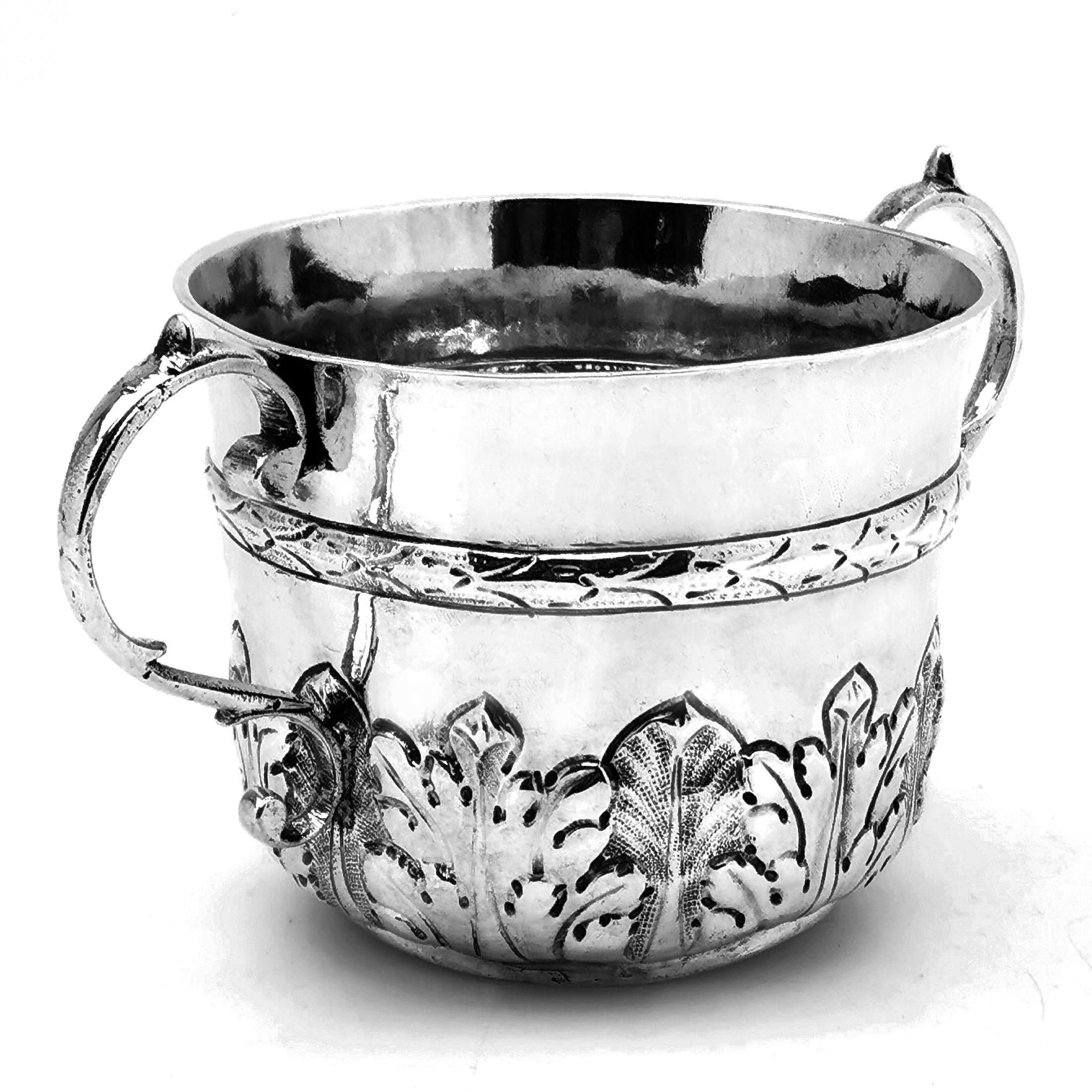 A lovely Antique 17th century James II solid Silver Porringer, decorated with a band of stylised leaf patterns around the lower half of the body, below a wreath style band around the centre. The Porringer has a pair of classic scroll handles and is