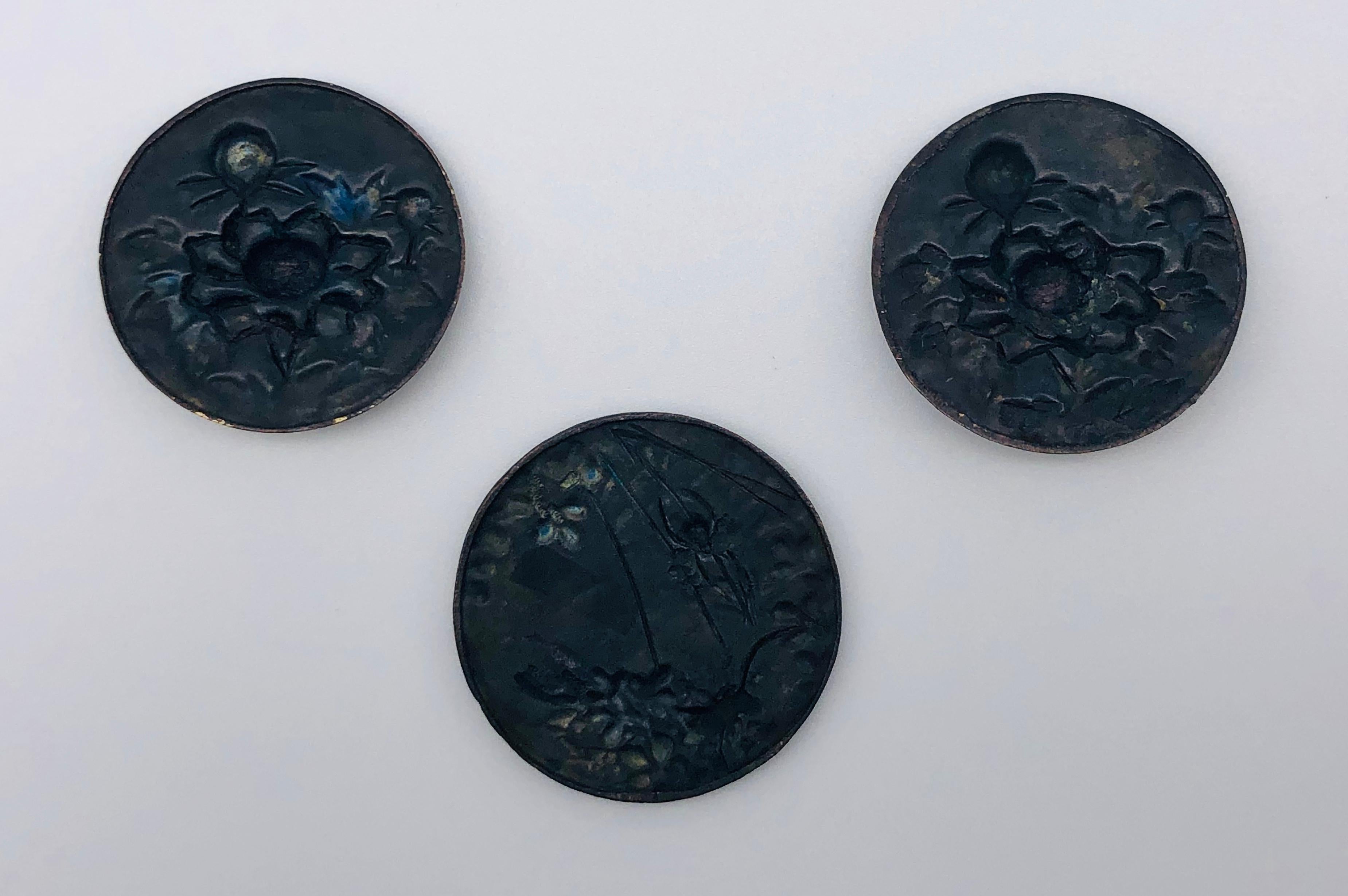 Two plaques are identical showing three peonies. One plaque, slightly larger, shows a butterfly, a grasshopper and a spider in its net. The three plaques are fine examples of Shakudo work dating from the 2nd half of the 19th century.

Diameter two