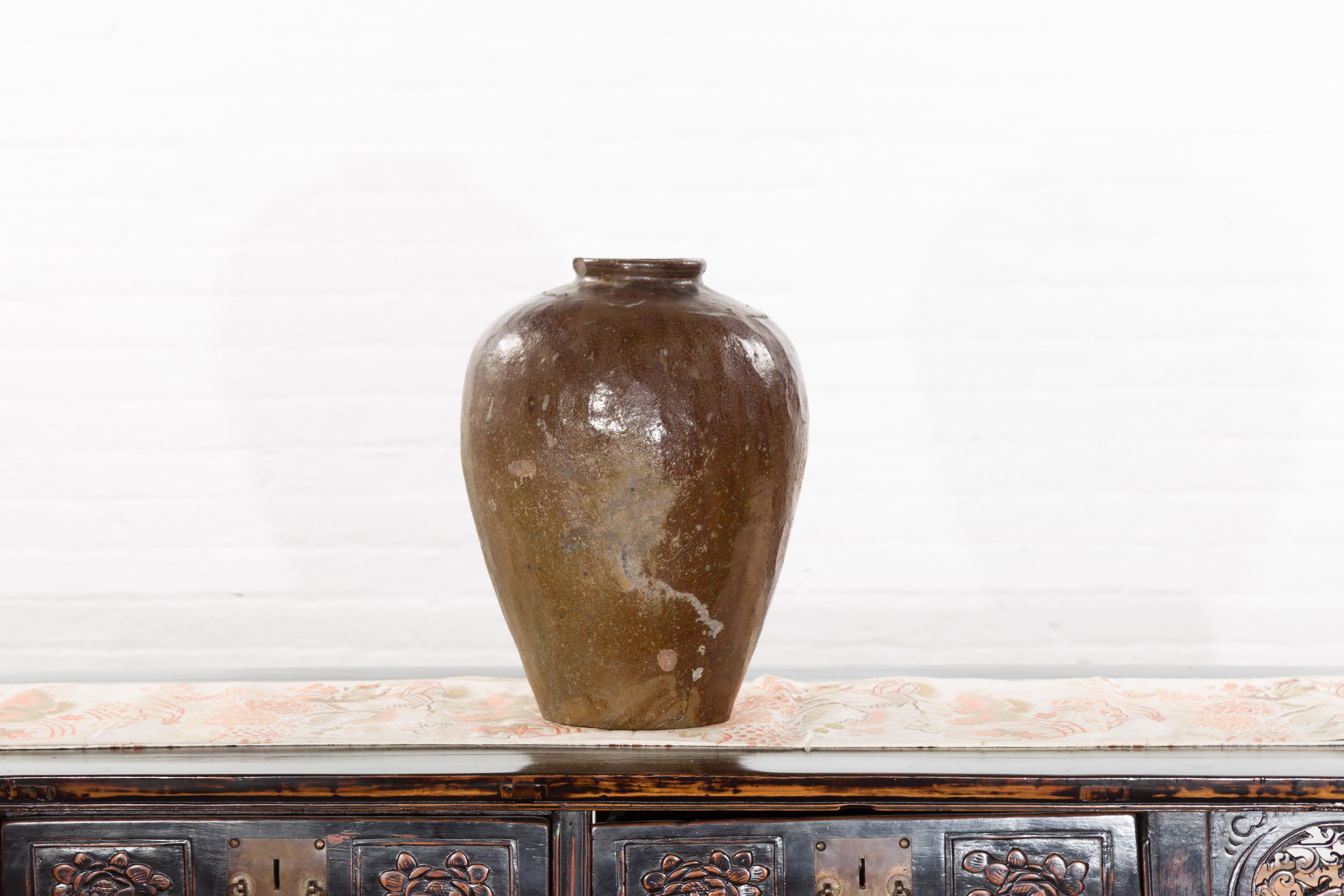 An antique Japanese brown water jar from the 19th century, with distressed patina. Sold as is, this Japanese water jar features a generous tapering body boasting a nicely weathered brown glaze. Topped with a circular beveled lip, this 19th century