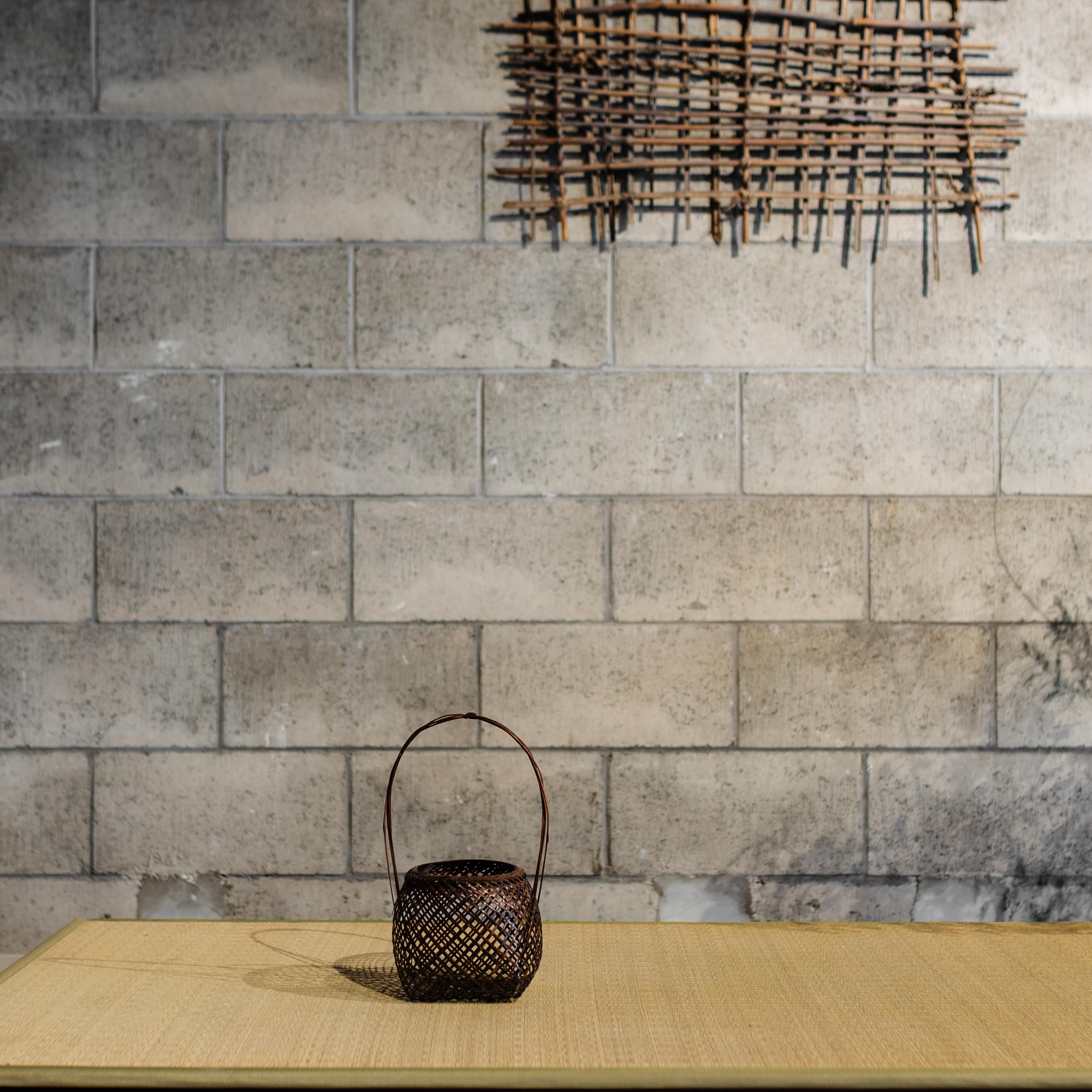 A refined example of Japanese bamboo craftsmanship, this handwoven basket features a gently rounded body and arched handle, showcasing a rhythmic open-weave pattern. Likely used for traditional flower arrangement or as a functional yet decorative