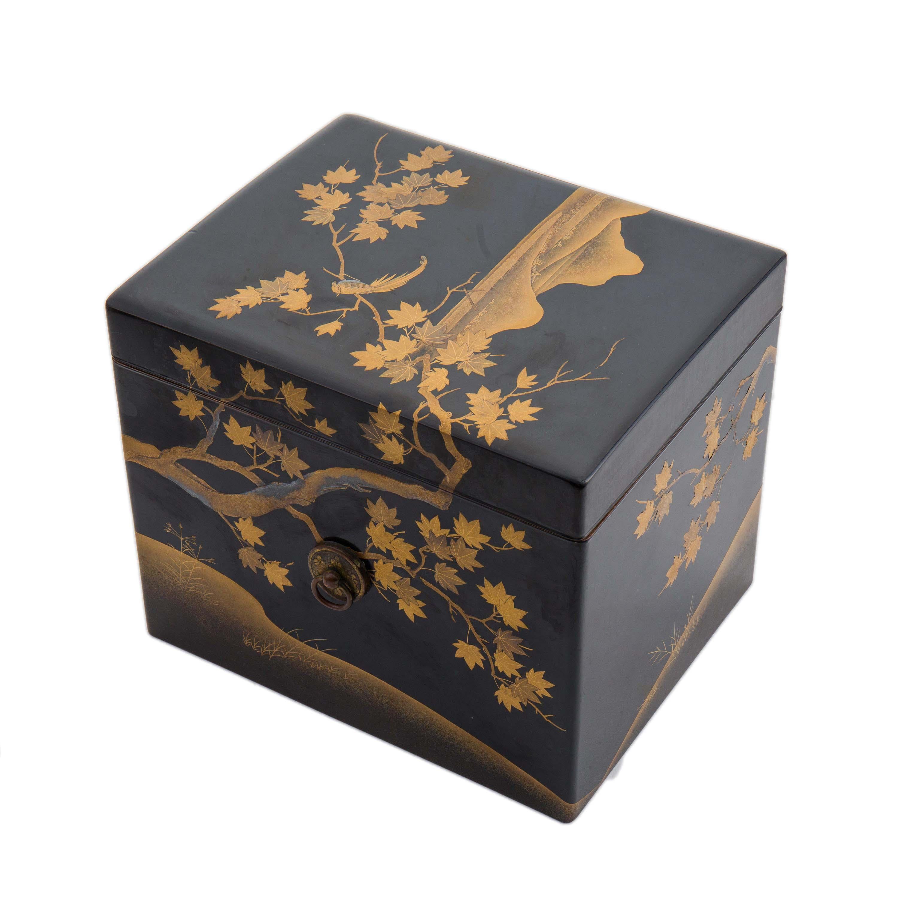 A Japanese Noh mask box, in black lacquer with a gold and silver maki e Rimpa style landscape design featuring a bird sitting in maple trees with mountains in the background. The detail is delicate and beautiful. It has bronze ring pull handles and