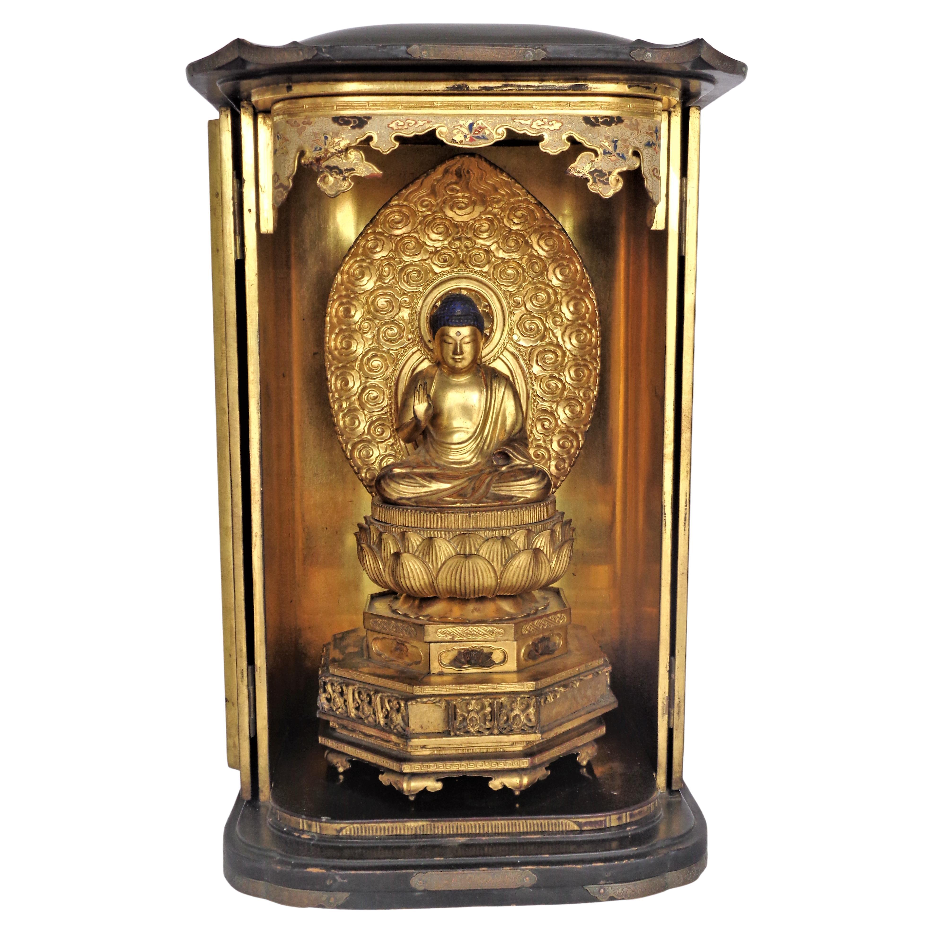 Antique large Japanese black lacquered traveling shrine with finely detailed patinated brass fittings / two hinged doors / gilded brass enameled upper arch / fully gilded interior / carved gilt wood Buddha Bodisattva seated Kannon figure on a carved