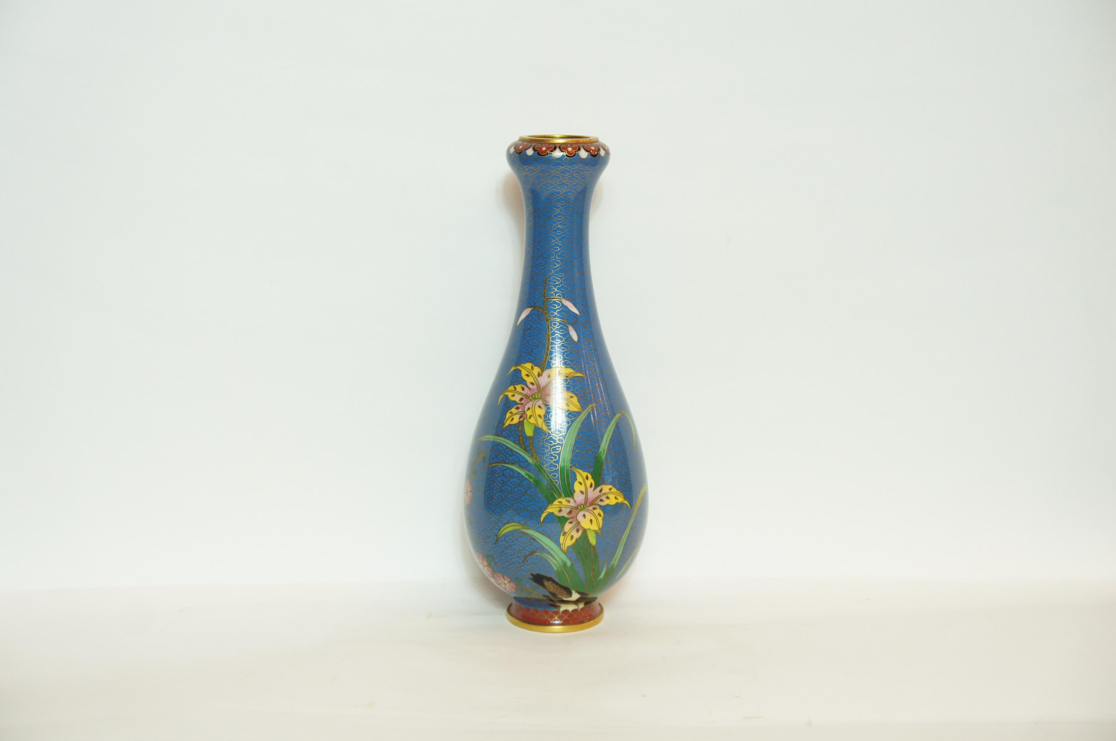 This is a blue flower vase made in Japan around 1950 in Showa era.
It is designed some flowers and butterflies. 
This style made with copper is called Shippou in Japanese.
The cloisonné technique was mastered in China in the early 19th century
