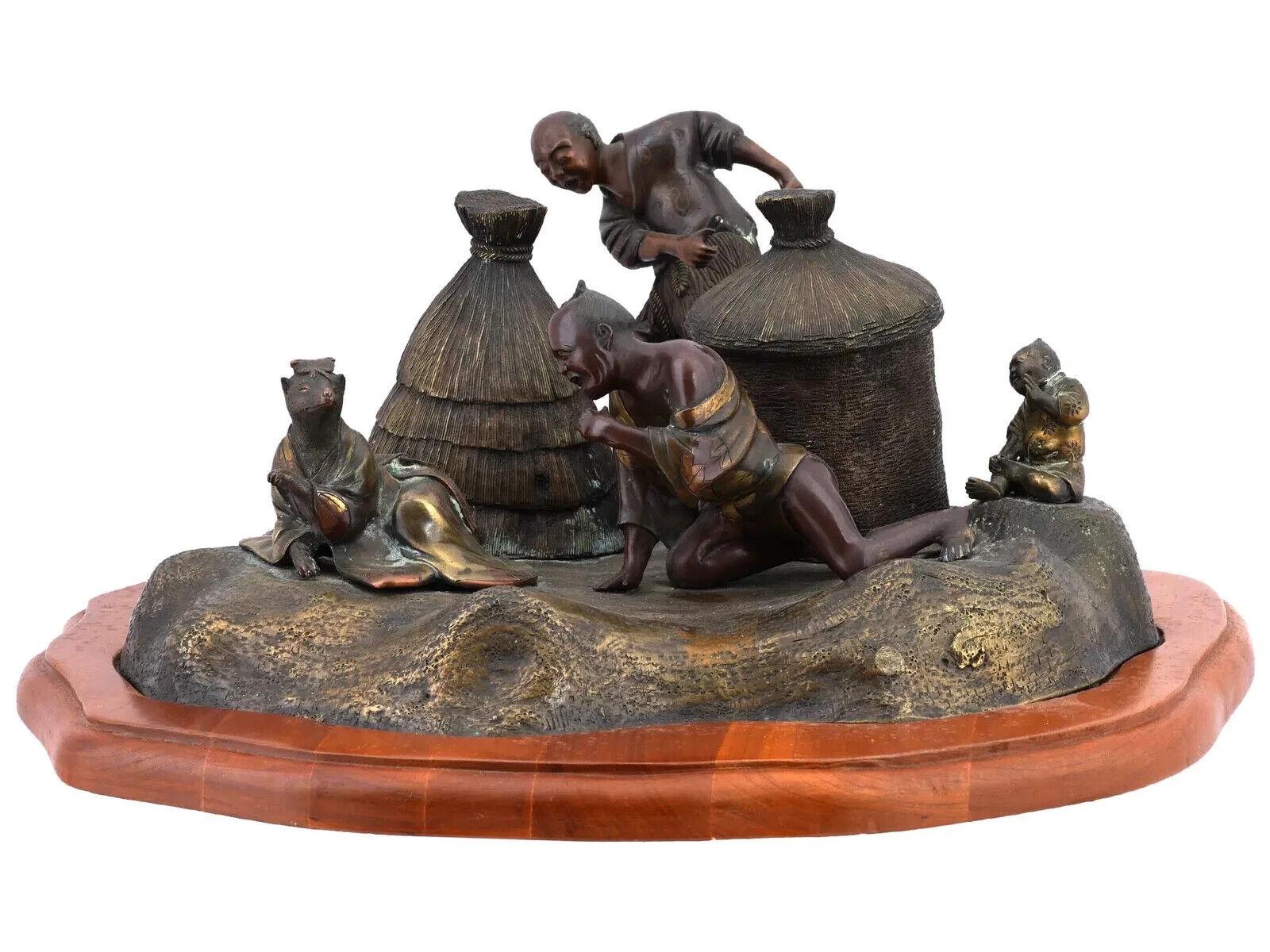 An antique Japanese bronze inkwell with tanuki. Meiji era, late 19th century. The inkwell is made in the form of a figurative dynamic scene depicting two peasants who have found a Tanuki werewolf in a womans dress. The cylindrical inkwell with a lid