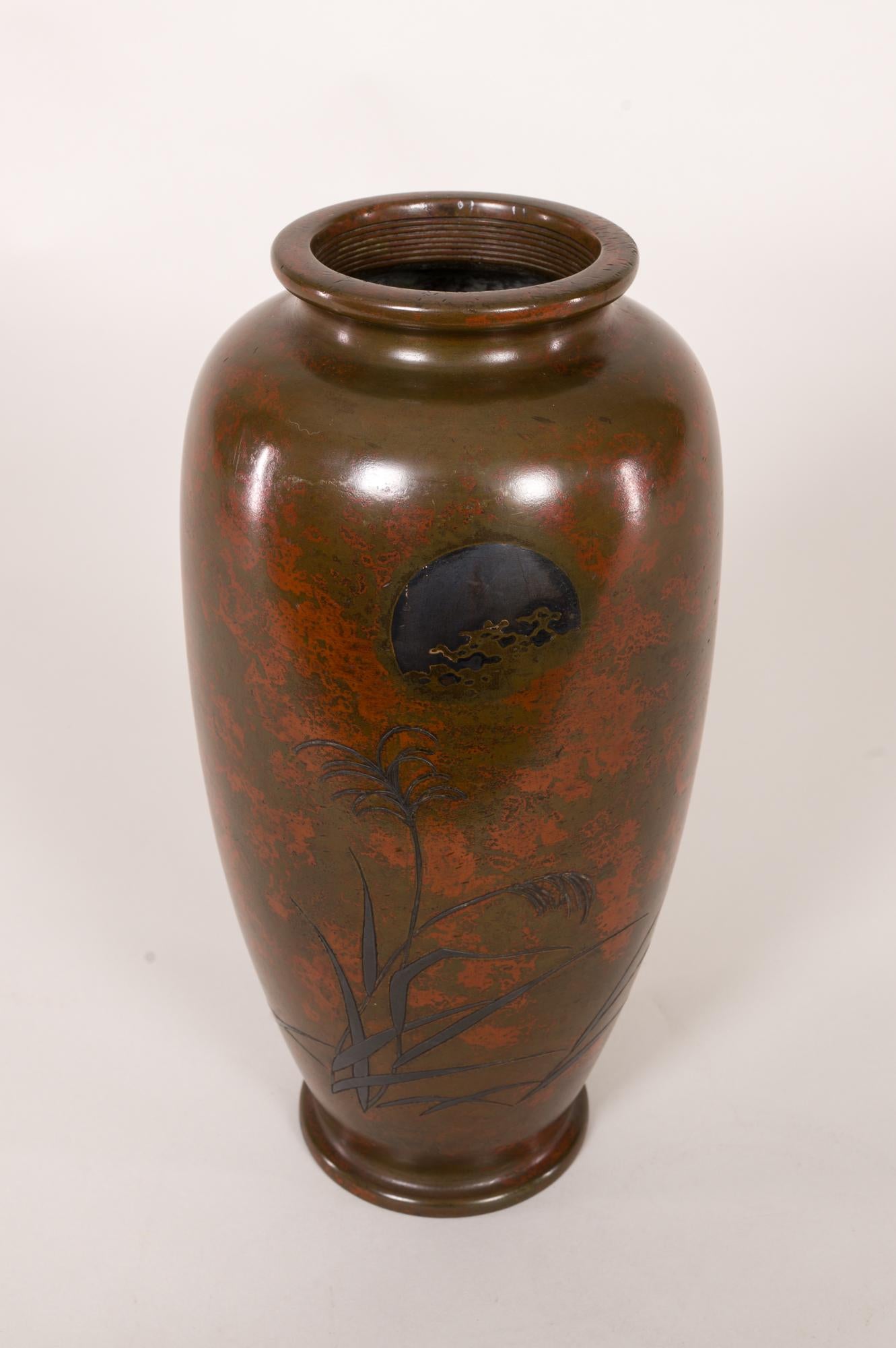 Vase japonais ancien en bronze avec paysage et patine rouge. Vase en bronze de la période Meiji (1868-1912) avec des herbes sauvages sous une lune argentée. Une sous-couleur rouge est exposée dans tout le vase, représentant les nuages. Le sceau de