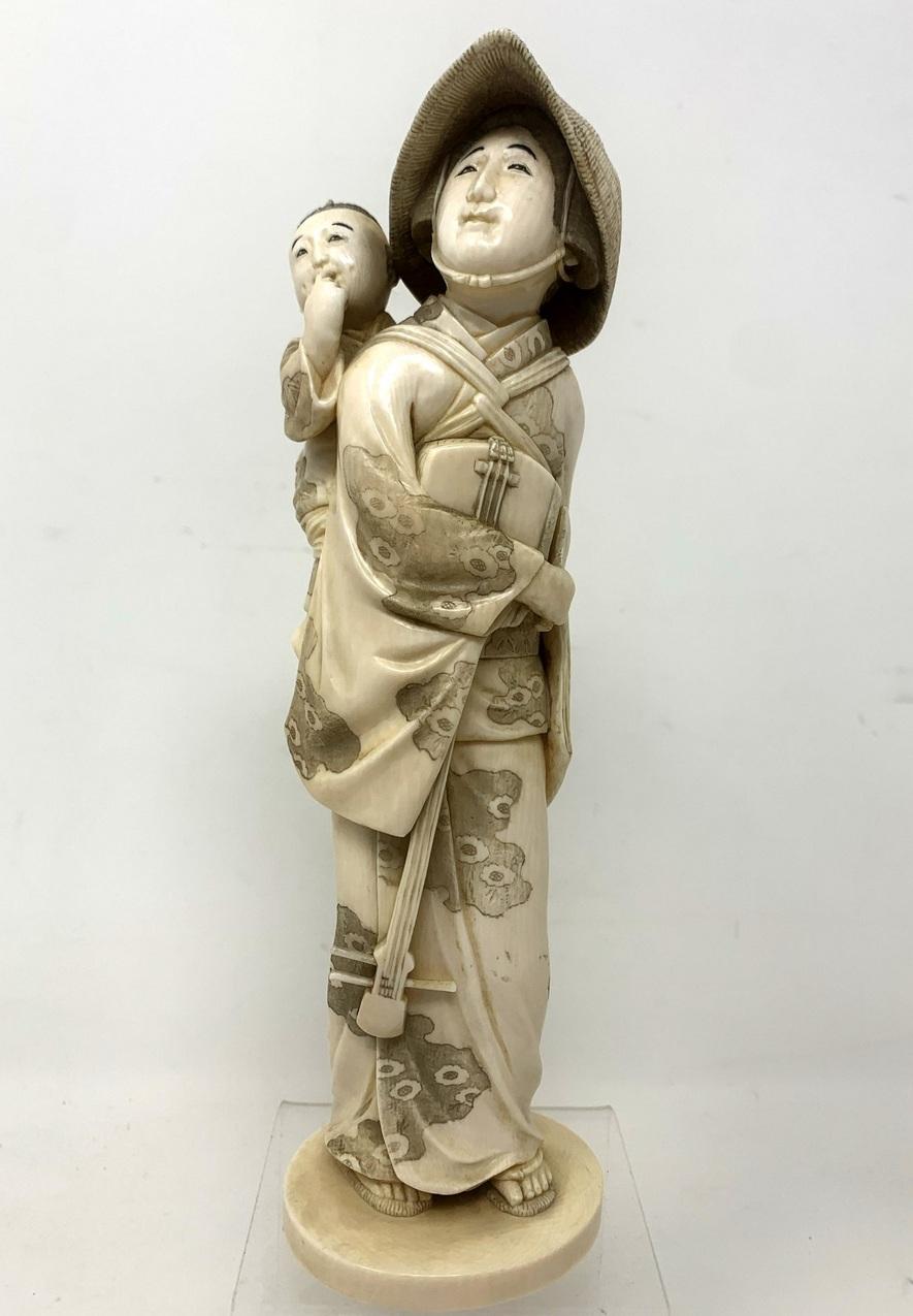 A Superb Example of a Japanese Carved and Stained Bone Standing Gentleman carrying a child, last quarter of the Nineteenth Century, possibly Meiji Period (1868-1912). 

Realistically modelled with etched and stained decoration and typical headdress.