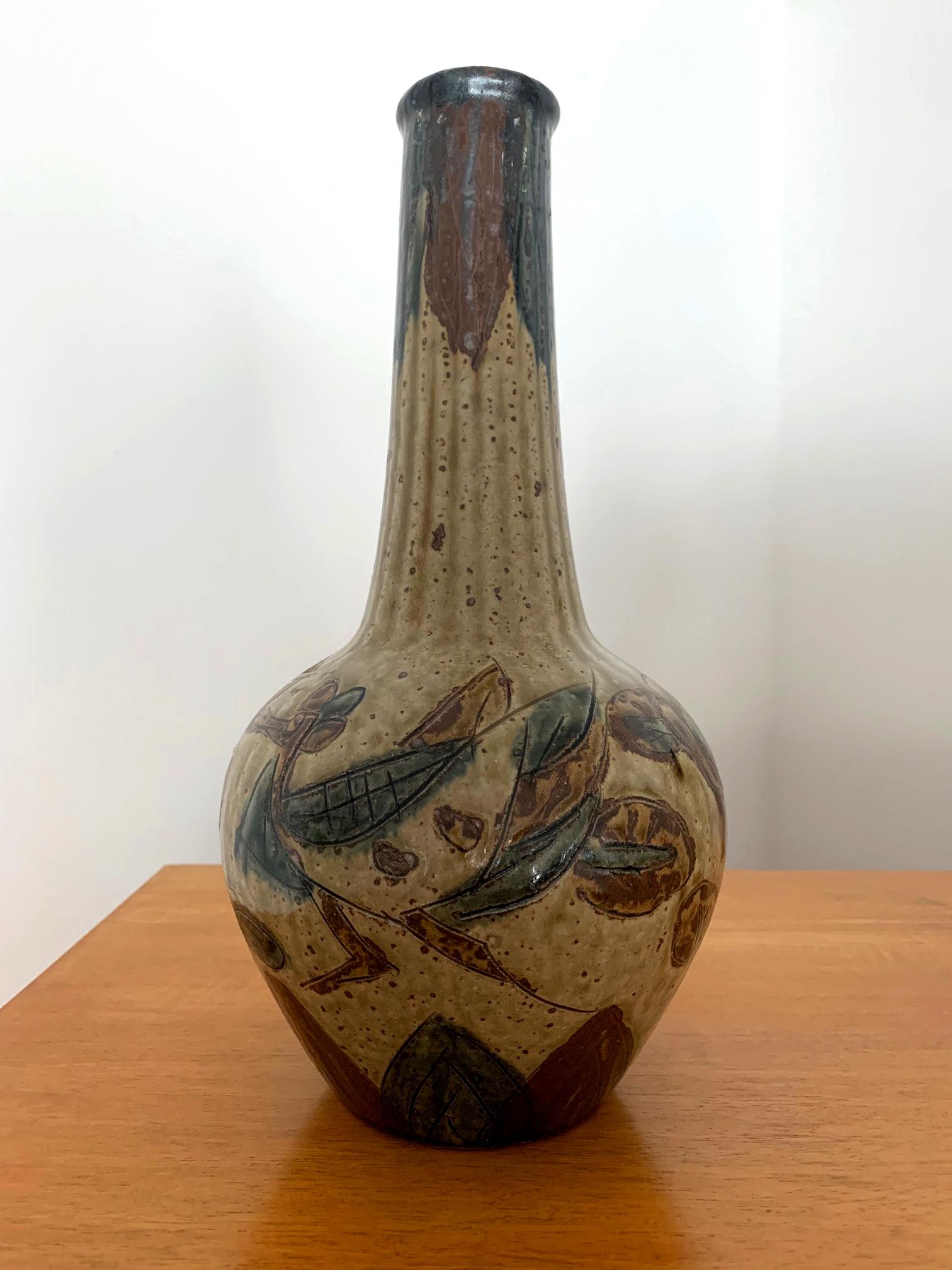 A charming Japanese stoneware vase with carved and over glaze dark green and aubergine enamel decoration on a yellow background circa early 20th century possibly made as a sake bottle or vase, the bottle features elongated flute lines along its body