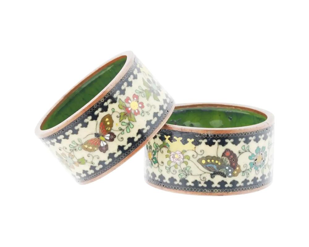 A pair of antique Japanese copper napkin rings with cloisonne enamel design. Late Meiji period, before 1912. The outer side of each ring is decorated with butterflies and flowers against the beige background. The inside of the rings is green.