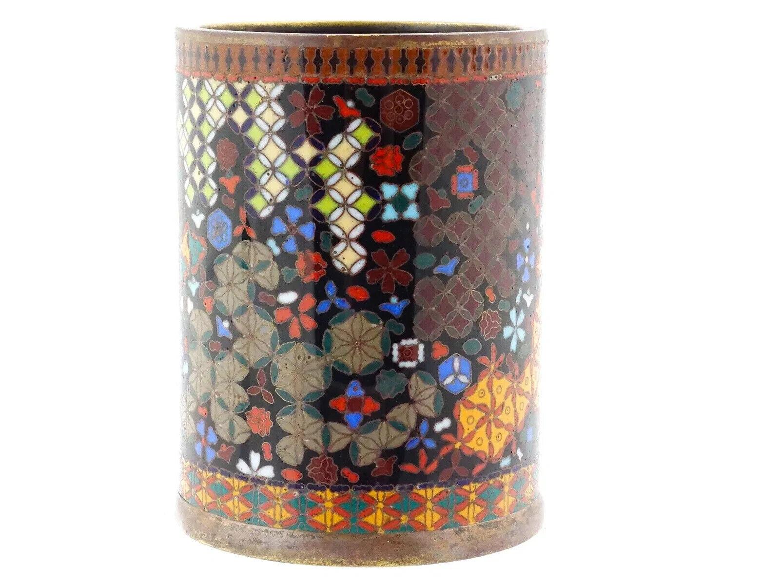 A  Bote de cepillo japonés de esmalte cloisonné sobre cobre dorado. Circa: finales del siglo XIX La vasija de forma cilíndrica está adornada con motivos policromos florales, de follaje y geométricos realizados en la técnica del Cloisonné. Sin