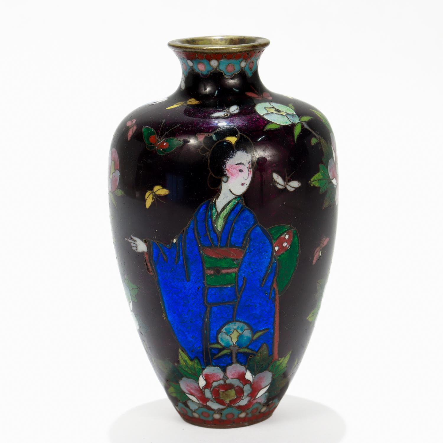 A fine antique Japanese cloisonne enamel cabinet vase. 

In brass with cloisonne enamel throughout.

Decorated with a geisha in blue kimono surrounded by numerous flowers and butterflies on a dark purple ground.

Simply a wonderful Japanese