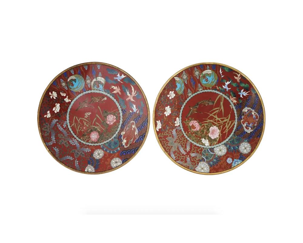 air of antique Japanese, late Meiji era, enamel over brass charger plates. The wares are enameled with a polychrome image of naturalistic ducks in blossoming flowers to the center surrounded by bird, floral, foliage, cloud, wavy patterns,