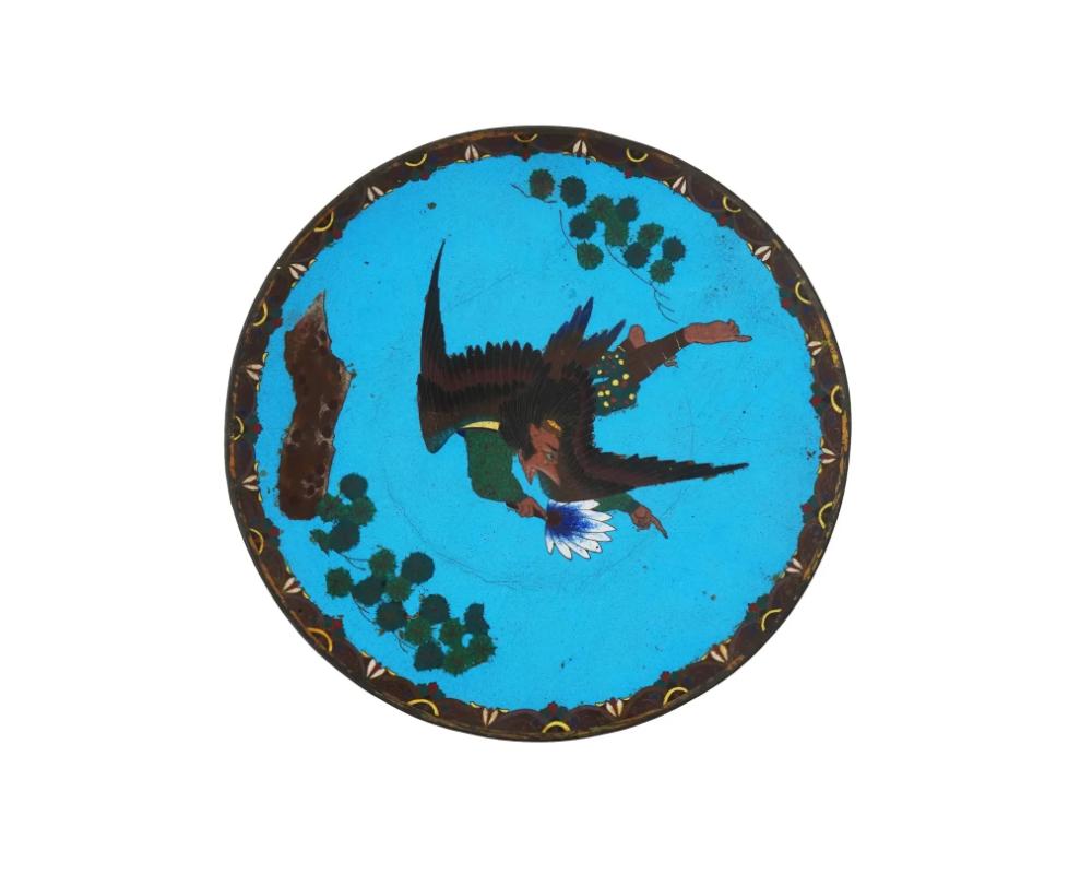 An antique Japanese enamel over copper charger plate, Meiji era, 1868 to 1912. The plate is adorned with a polychrome enamel image of a mythical creature Tengu on a turquoise ground made in the Cloisonne technique. The border is covered with