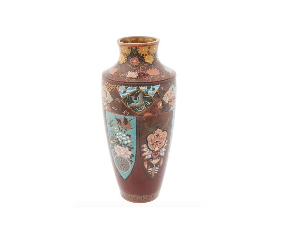 An antique Japanese enamel metal vase. The amphora shaped vase is enameled with polychrome medallions with birds, Phoenix birds, insects, blossoming flowers surrounded by floral, foliage and geometrical motifs made in the Cloisonne technique. The