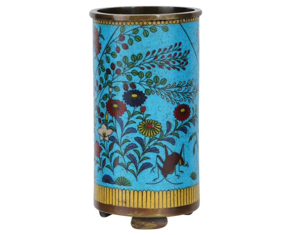 An antique Japanese late Meiji Era cylindrical shaped enamel over copper brush pot. Circa: late 19th century. The cylindrical form pot is enameled with a polychrome image of a burd and a bug in a garden with blossoming flowers made in the Cloisonne