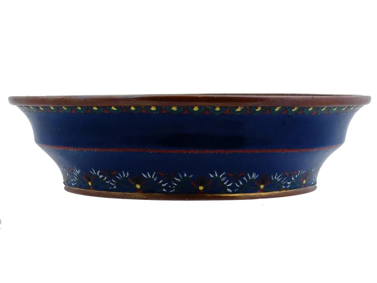 Antiguo plato esmaltado japonés, con la imagen central de un dragón sobre fondo rosa. El borde está adornado con intrincados motivos florales multicolores. Se complementa con bordes exteriores de latón. Alrededor del siglo XIX. Coleccionables
