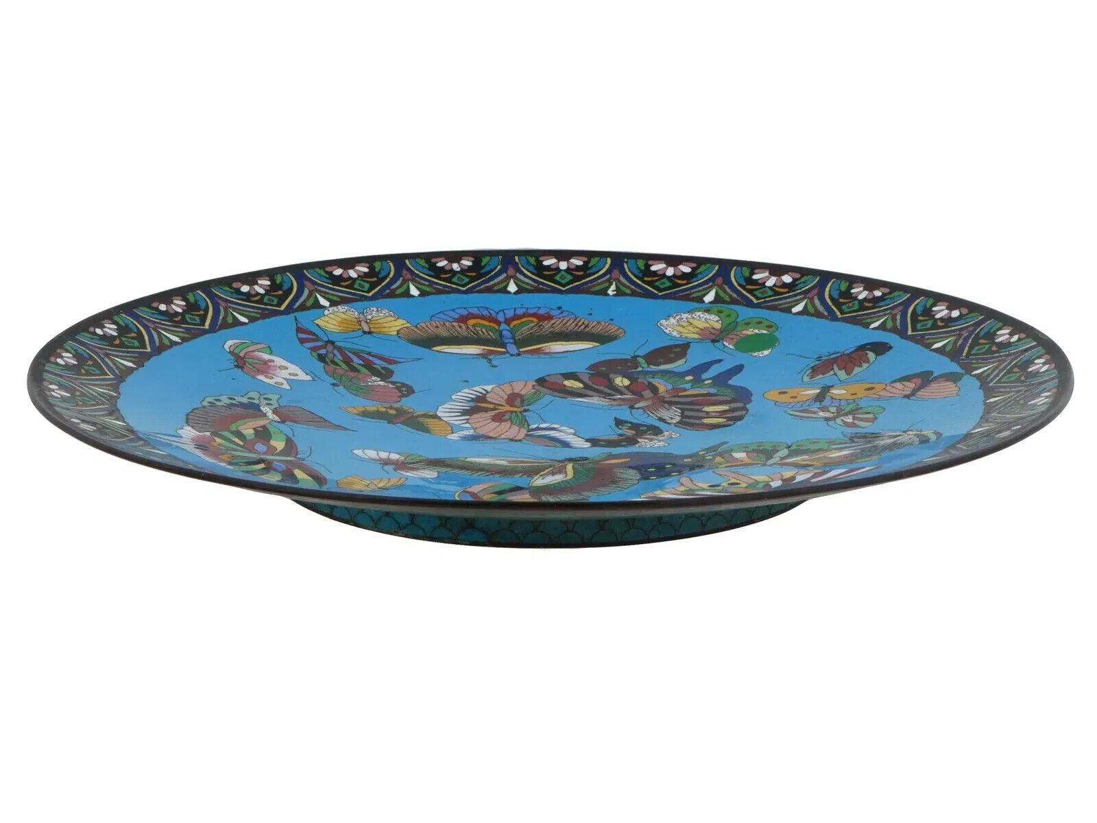 Un'antica placca giapponese in smalto su rame. Il piatto è smaltato con il disegno di una farfalla policroma circondata da motivi floreali e di fogliame realizzati con la tecnica Cloisonne su un fondo turchese. Il retro è ornato da un motivo a