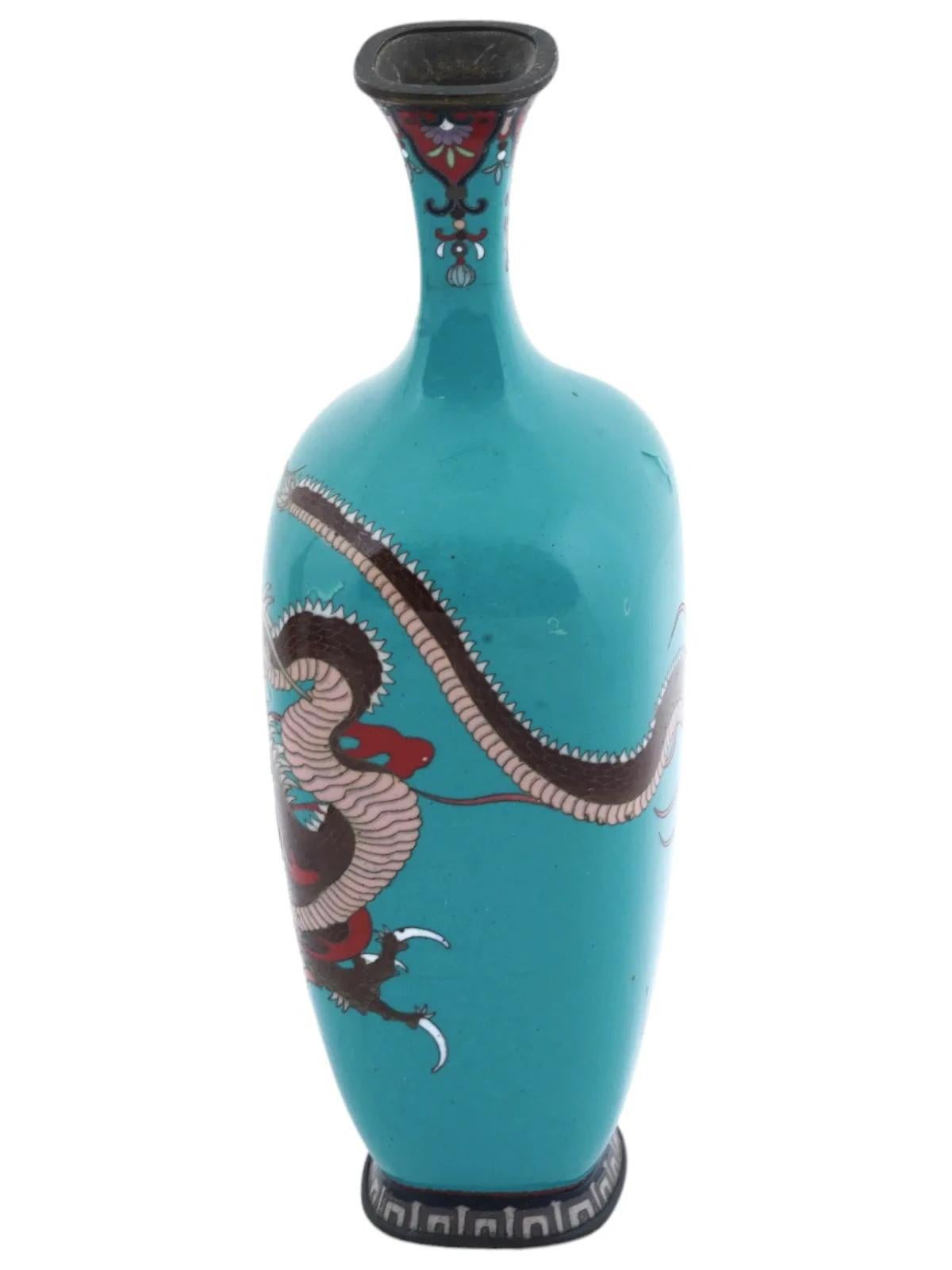 An antique Japanese late Meiji era vase of a baluster shape with a narrow fluted neck. The metal vase is adorned with a polychrome image of a dragon made in the Cloisonne technique on a bright turquoise ground. The base is adorned with a geometric