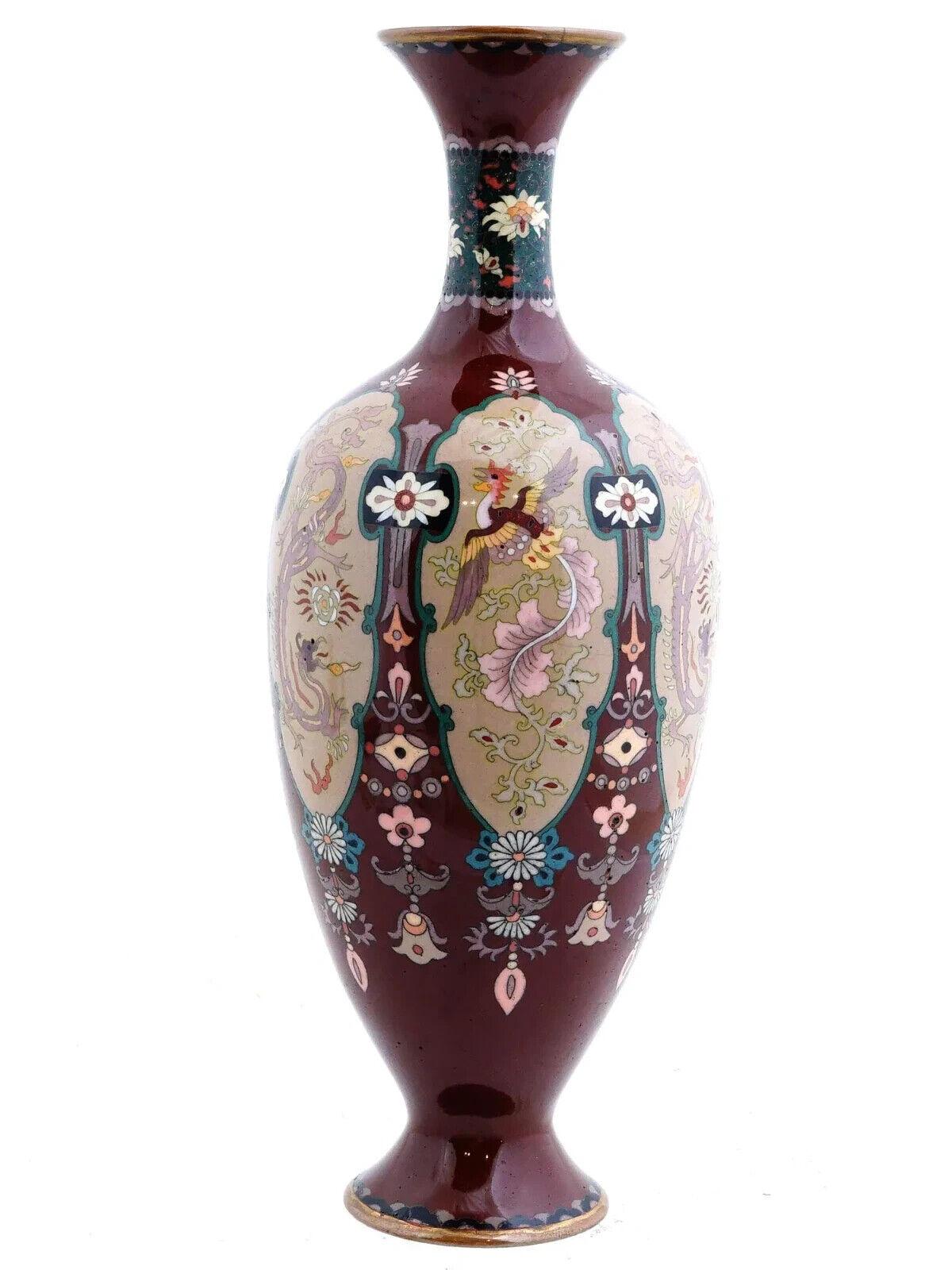 An antique Japanese cloisonne enamel vase of baluster form, featuring a tiny neck and flared mouth. The vase is adorned with panels set against a red ground, showcasing floral motifs. Each panel depicts a dragon or phoenix bird. Circa 19th century.