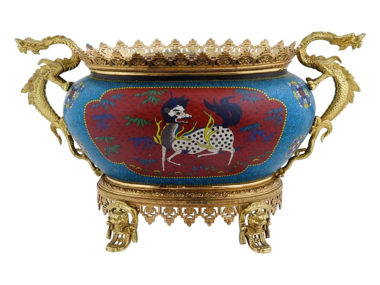 An antique Japanese decorative cloisonne enamel vase with a gilt bronze base and handles. It has a rounded, bowl like shape of a blue color with floral and swirl patterns, adorned with two red medallions depicting mythical animals: Qilin and Fenix.