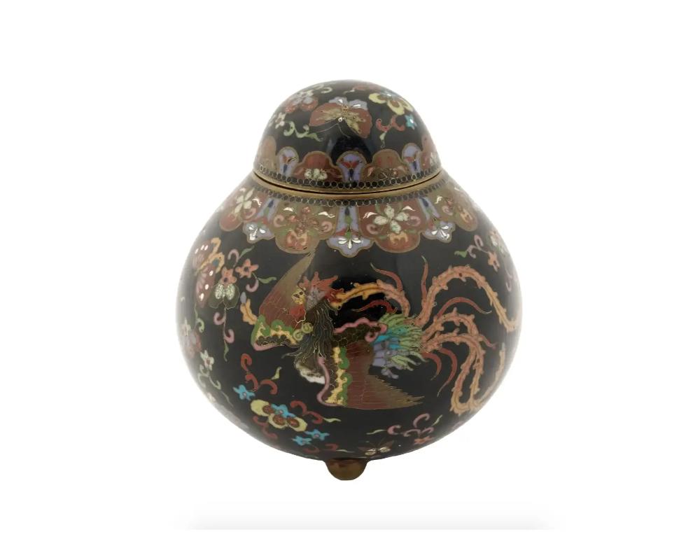 An antique Japanese Meiji era tripod and covered enamel gilt metal ginger jar.

The jar is enameled with polychrome images of a Phoenix bird, butterflies and blossoming flowers and foliage motifs made in the Cloisonne technique.

The neck is adorned