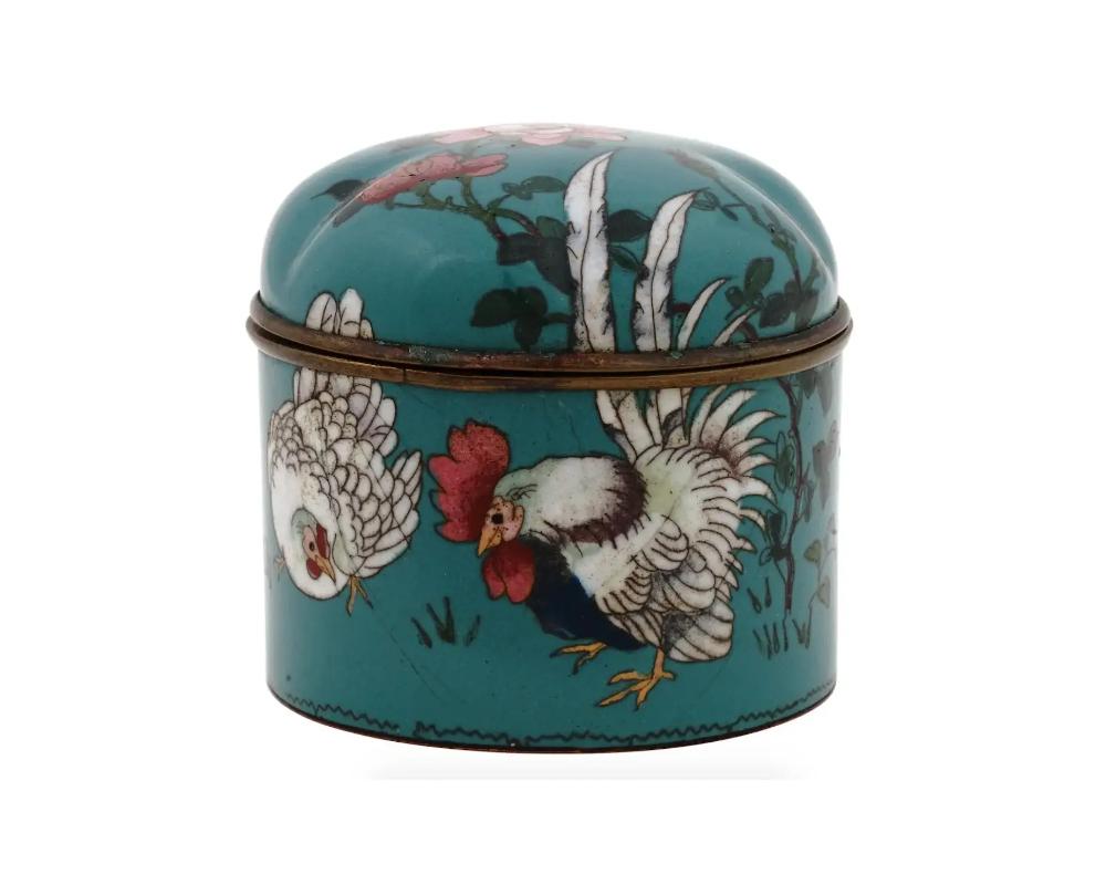 An antique Japanese Meiji era covered enamel over brass trinket or jewelry box. Circa: late 19th century to early 20th century. The ware is enameled with a polychrome image of a rooster and a hen in blossoming flowers with butterflies on the