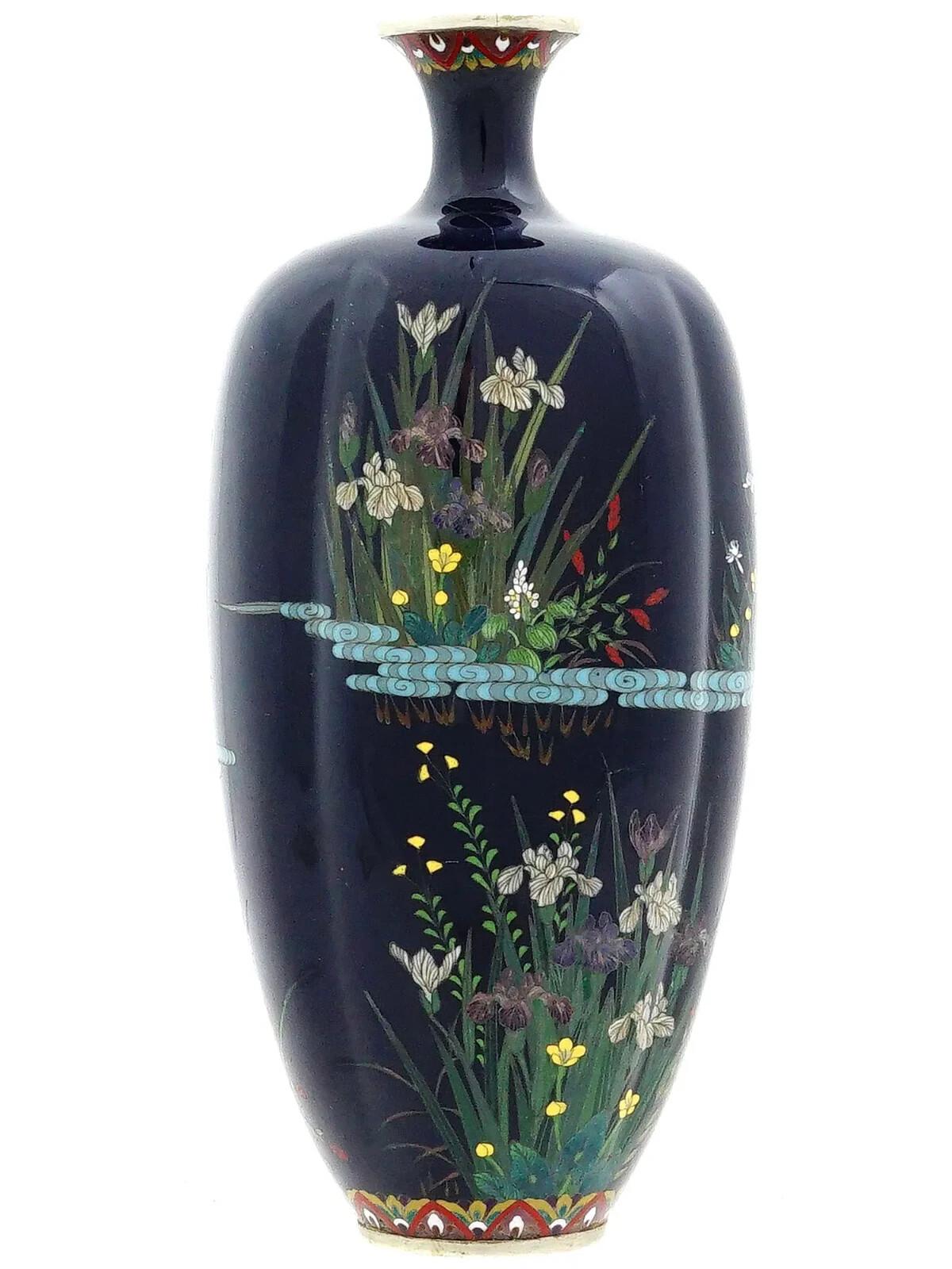 Vase japonais en fil d'argent et émail. Le vase en forme d'urne est émaillé d'un motif polychrome représentant des grues dans un paysage d'étang avec des fleurs épanouies, réalisé selon la technique du cloisonné. La base et le col sont ornés de