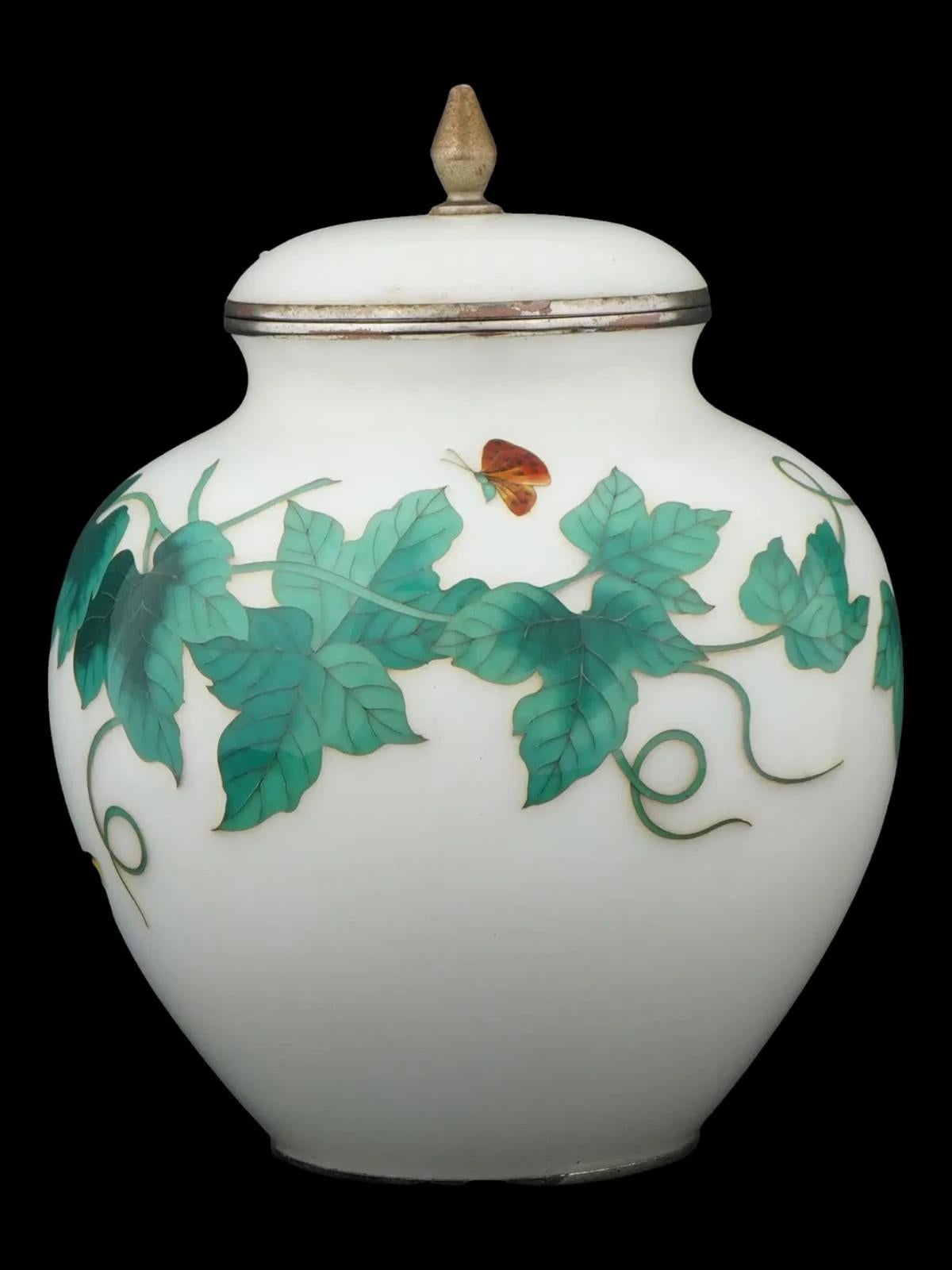 An antique Japanese Ando Jubei cloisonne rounded jar from the Meiji period. The vase is decorated with foliate image with butterflies. It features a fitted lid with a decorative finial. The rim of the vase and the base of the lid are lined with a