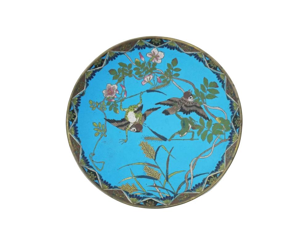 An antique Japanese late Meiji era decorative enamel over copper plate or charger. The interior of the plate is adorned with a polychrome design of sparrows and frogs in blossoming flowers and plants on the turquoise ground made in the Cloisonne